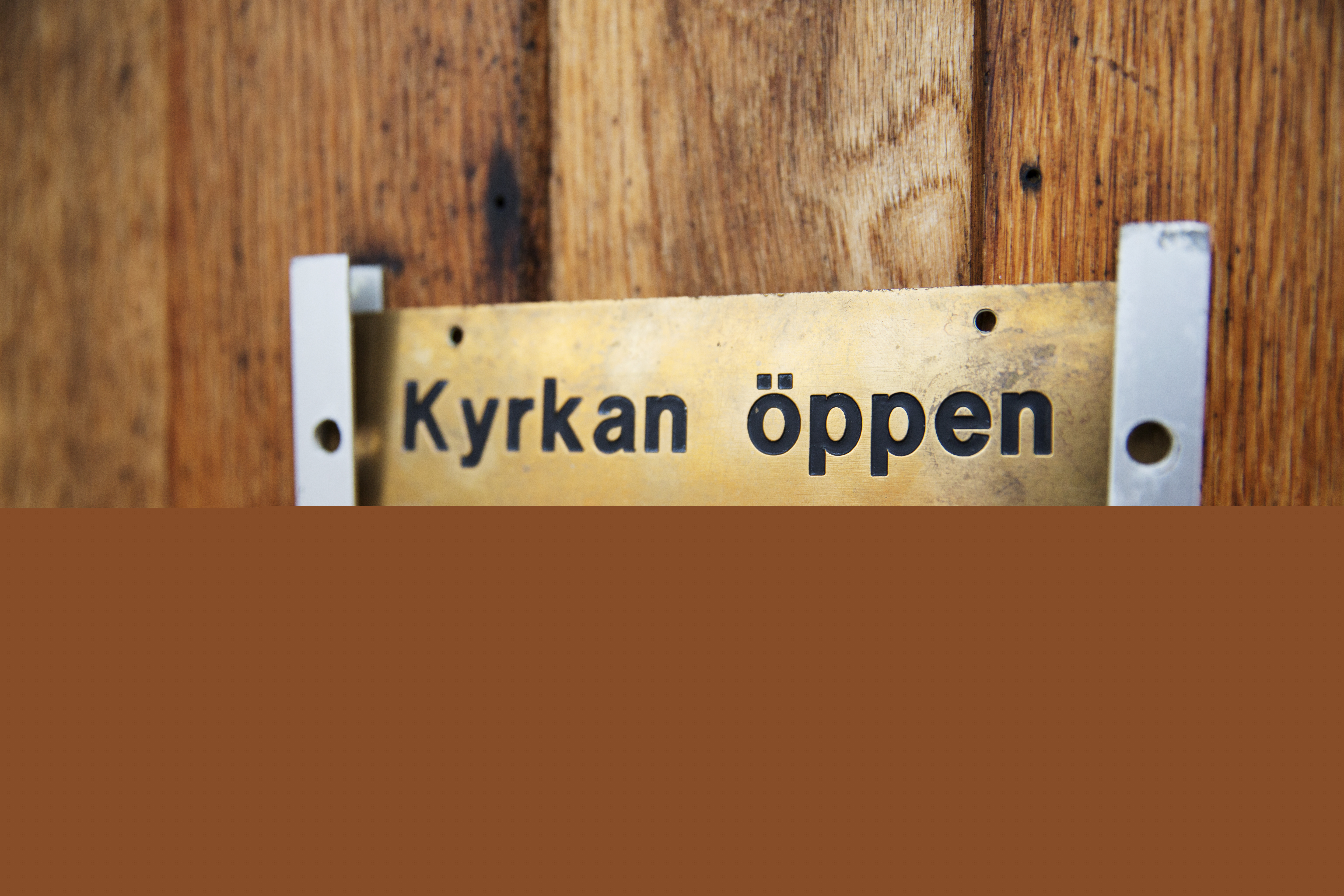En skylt på en dörr med texten Kyrkan öppen välkommen in.