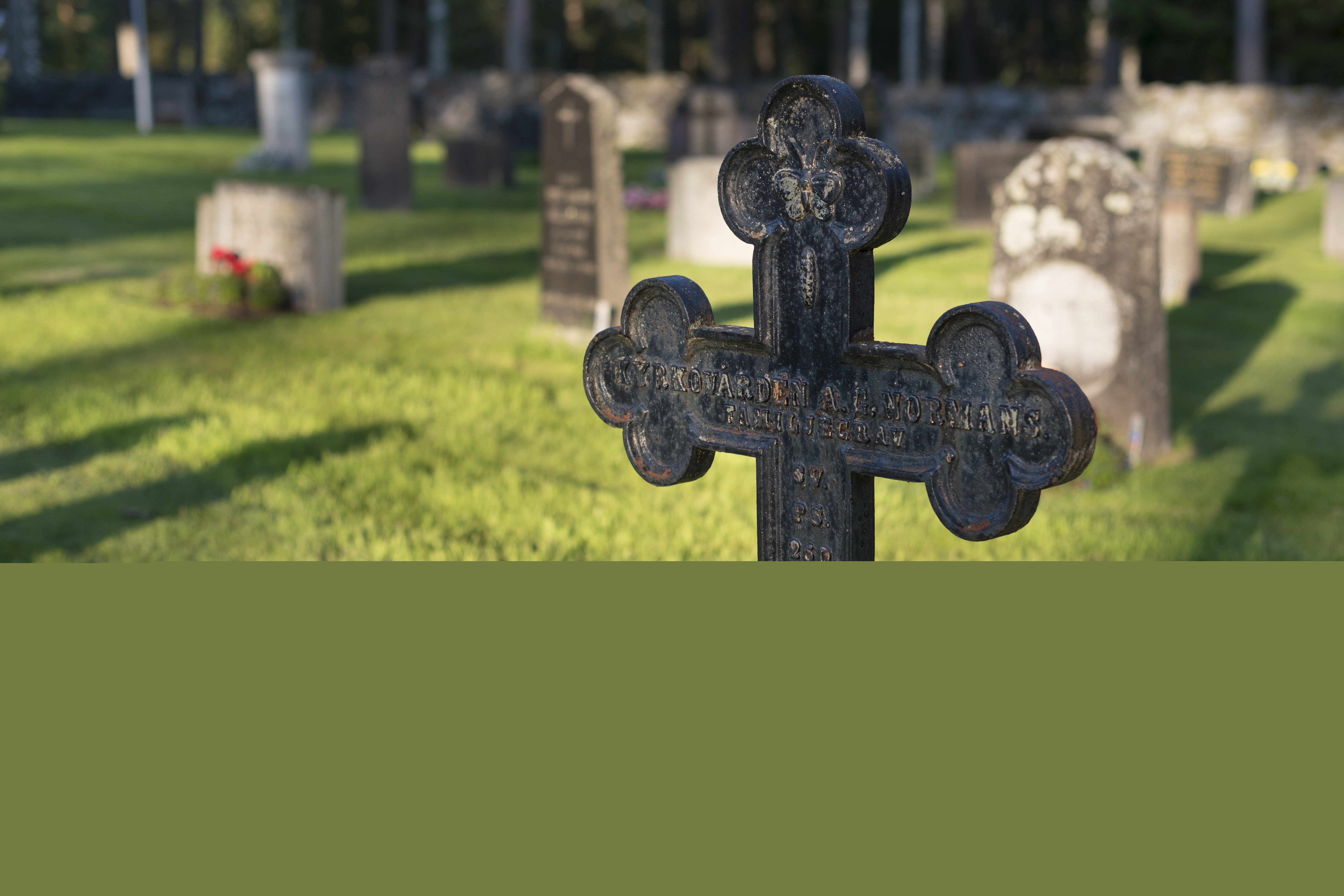 Ett gravkors i järn på en kyrkogård.