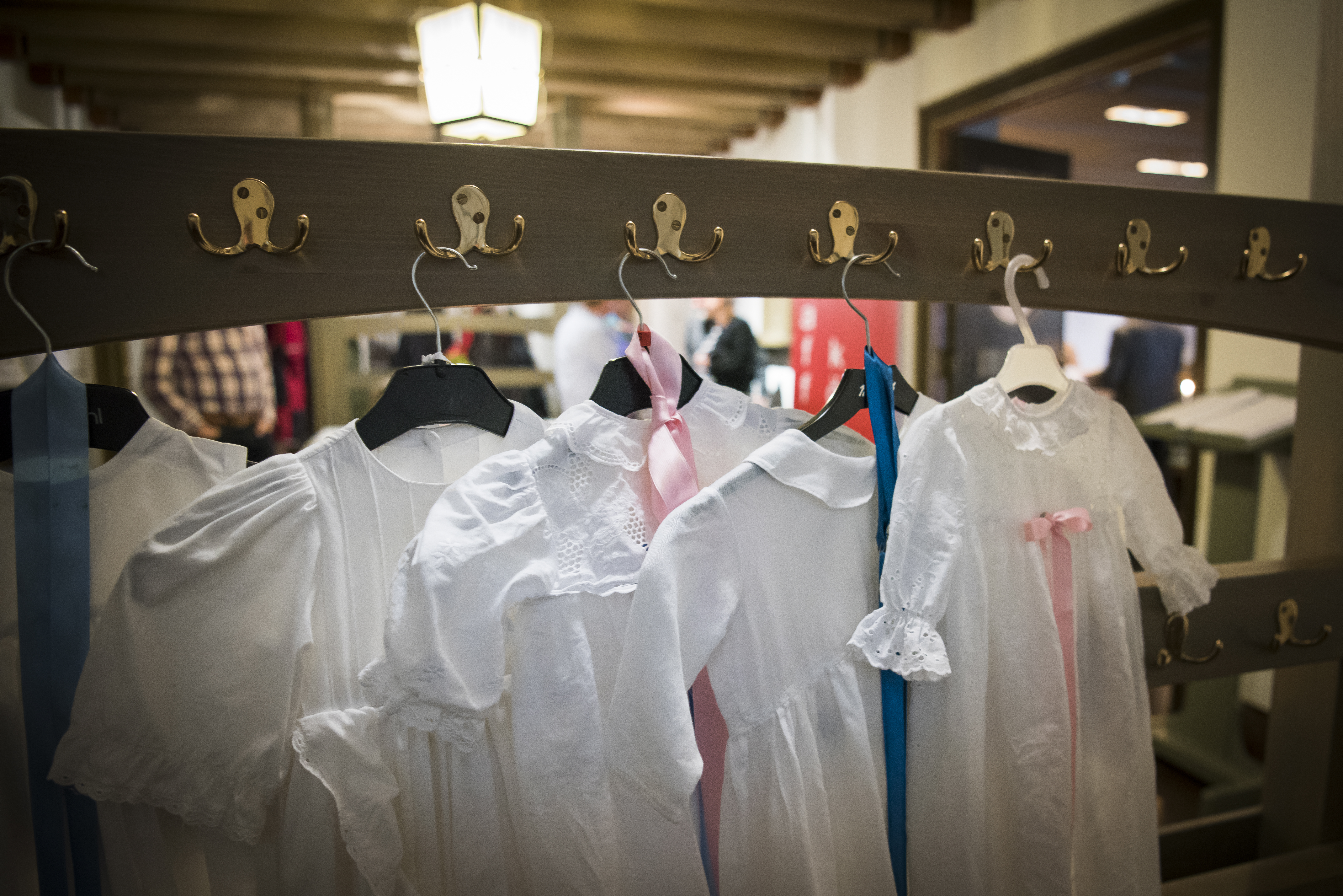 Dopklänningar hänger i galgar på några krokar.
