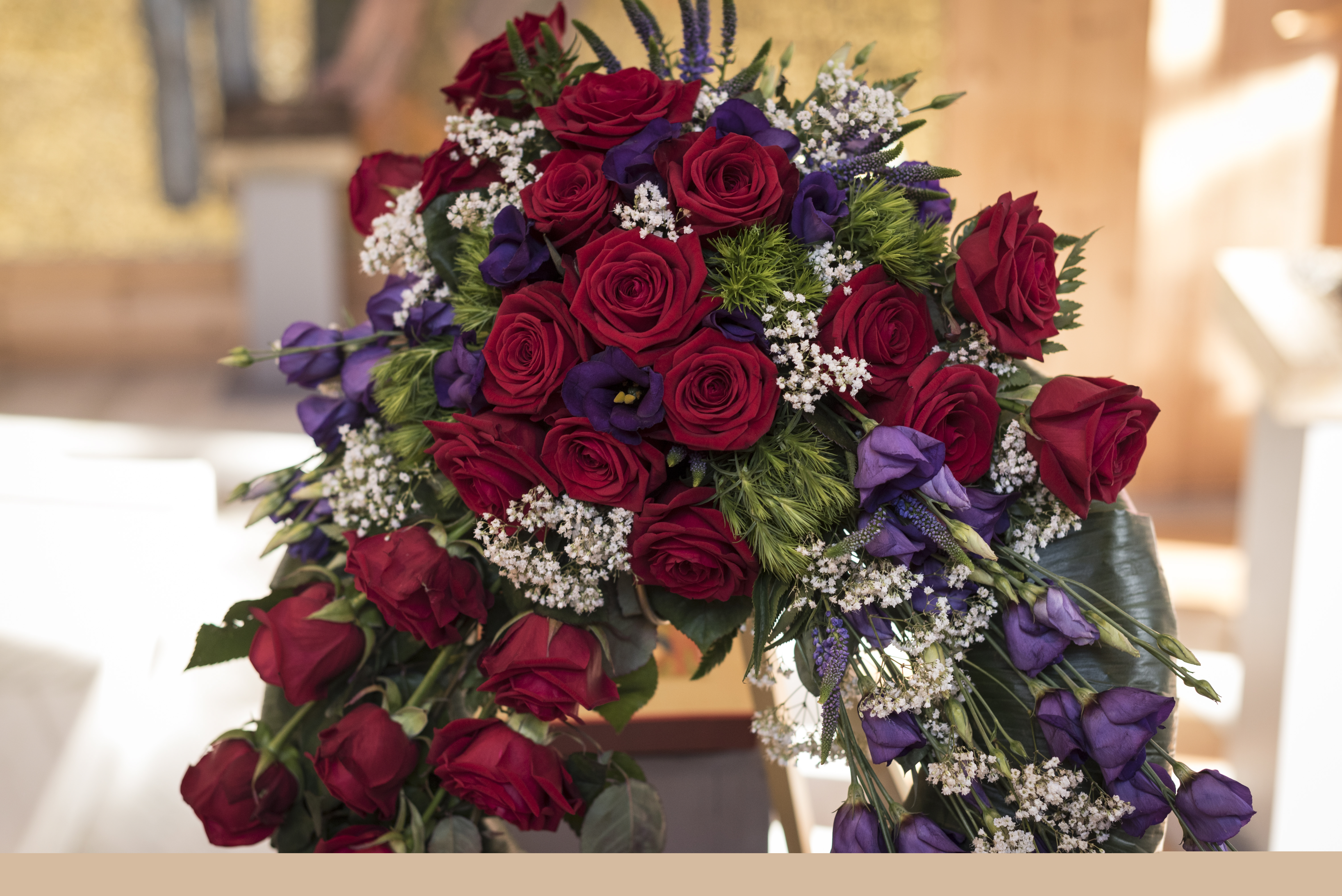 En begravningsbukett av röda och lila blommor.