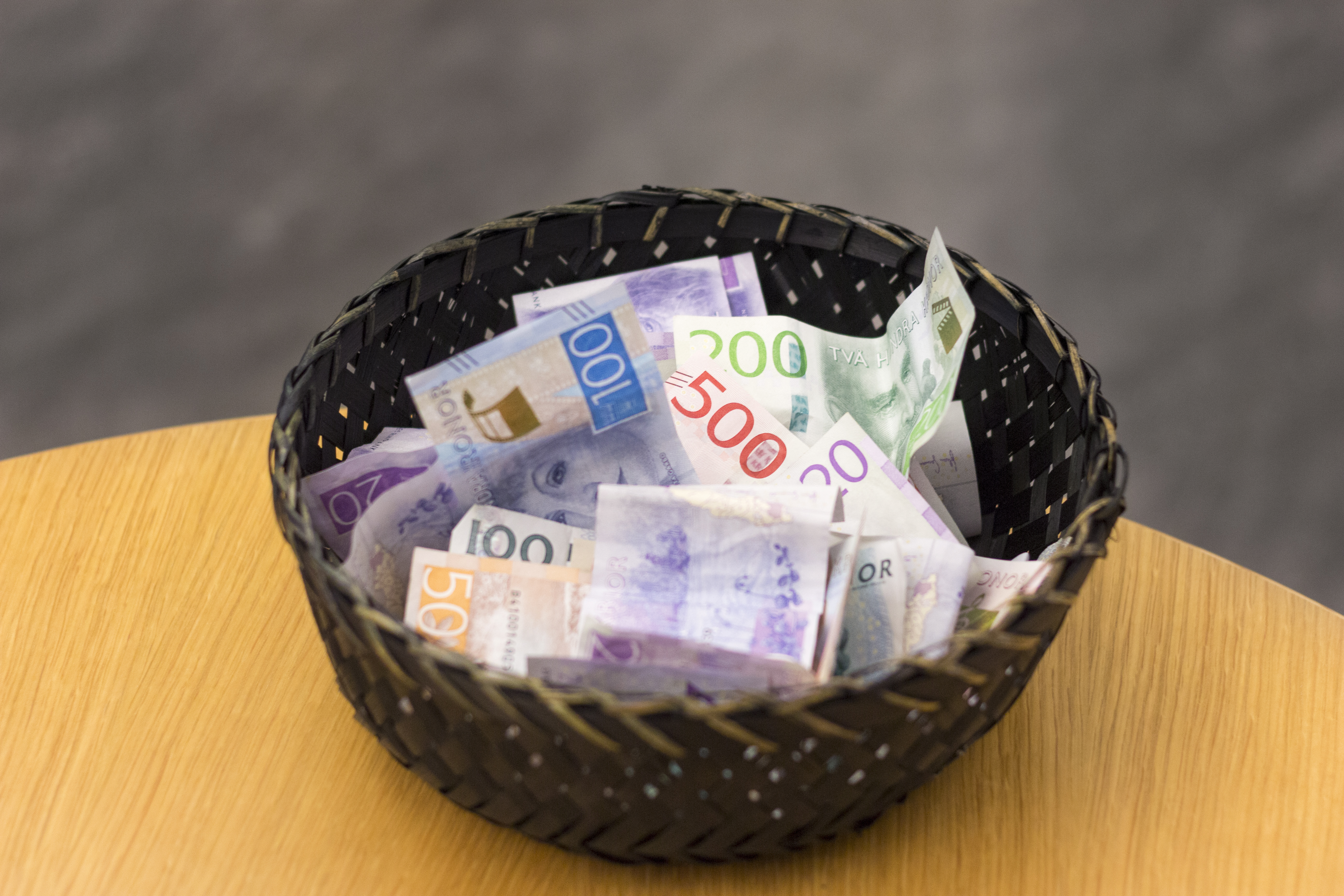 En korg fylld med sedlar står på ett bord.