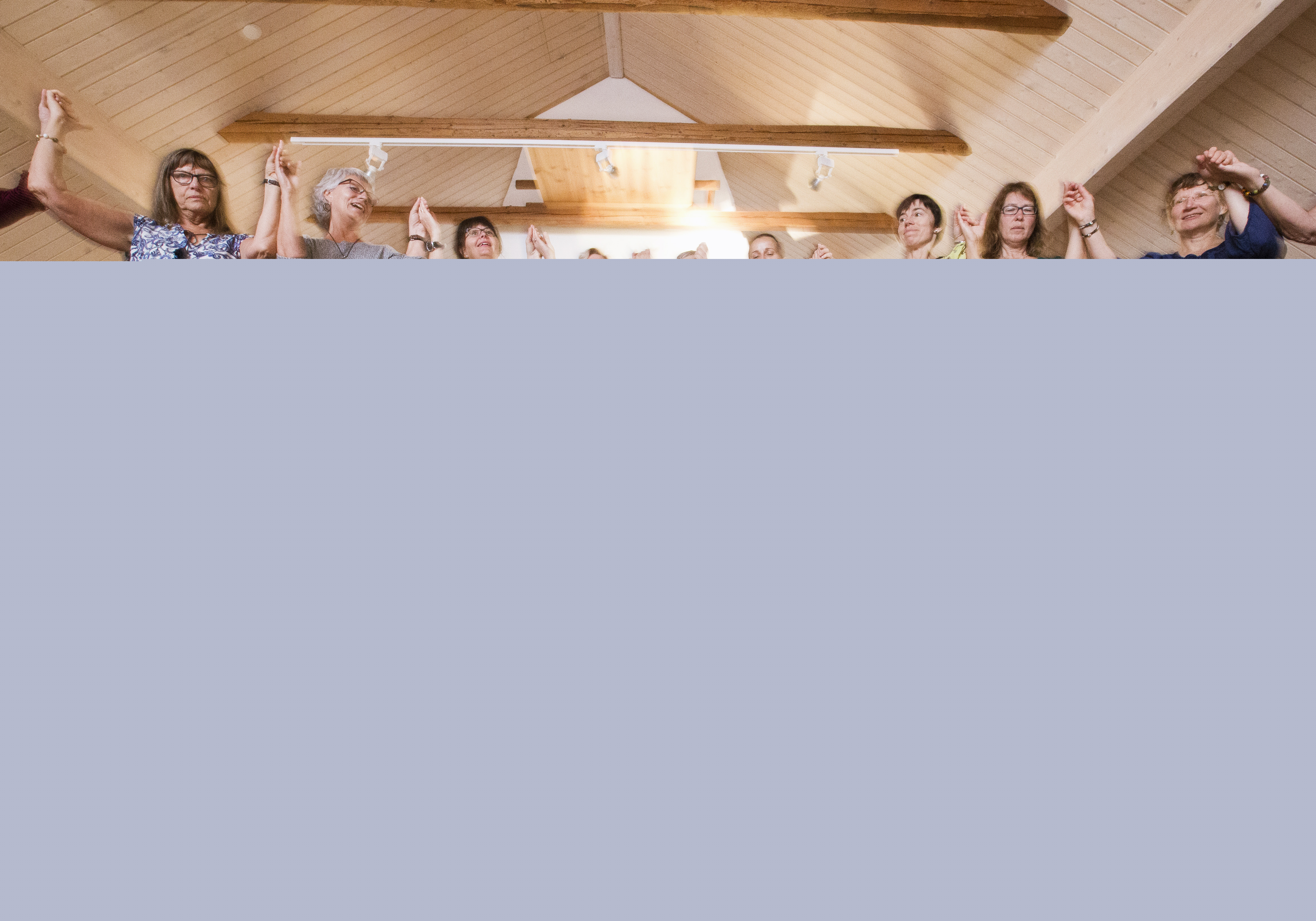 Några kvinnor dansar ringdans runt en skål med vatten och olika frukter som står på golvet.