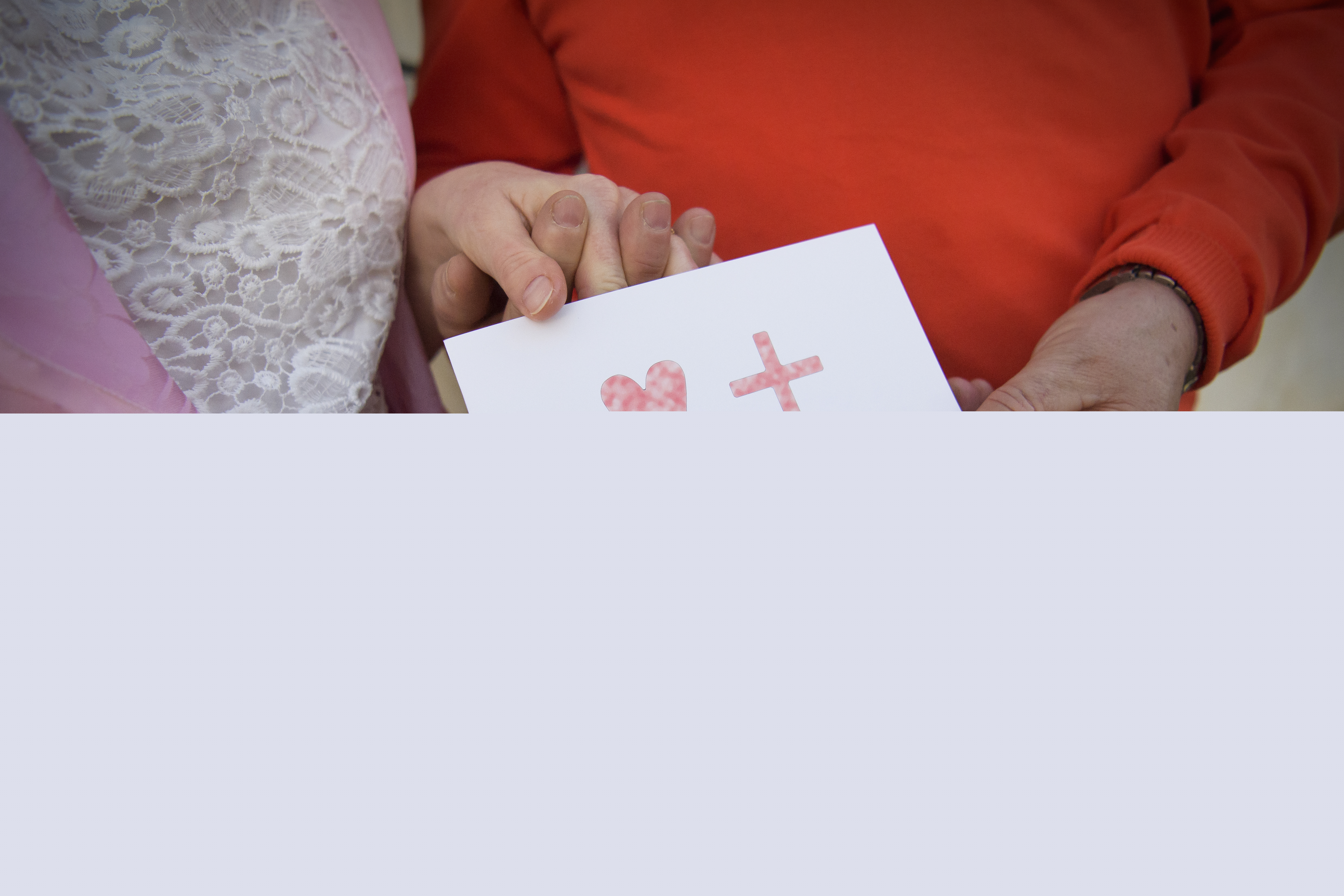 En man och en kvinna håller i ett papper med ett hjärta, ett kors och texten Vigselbevis.