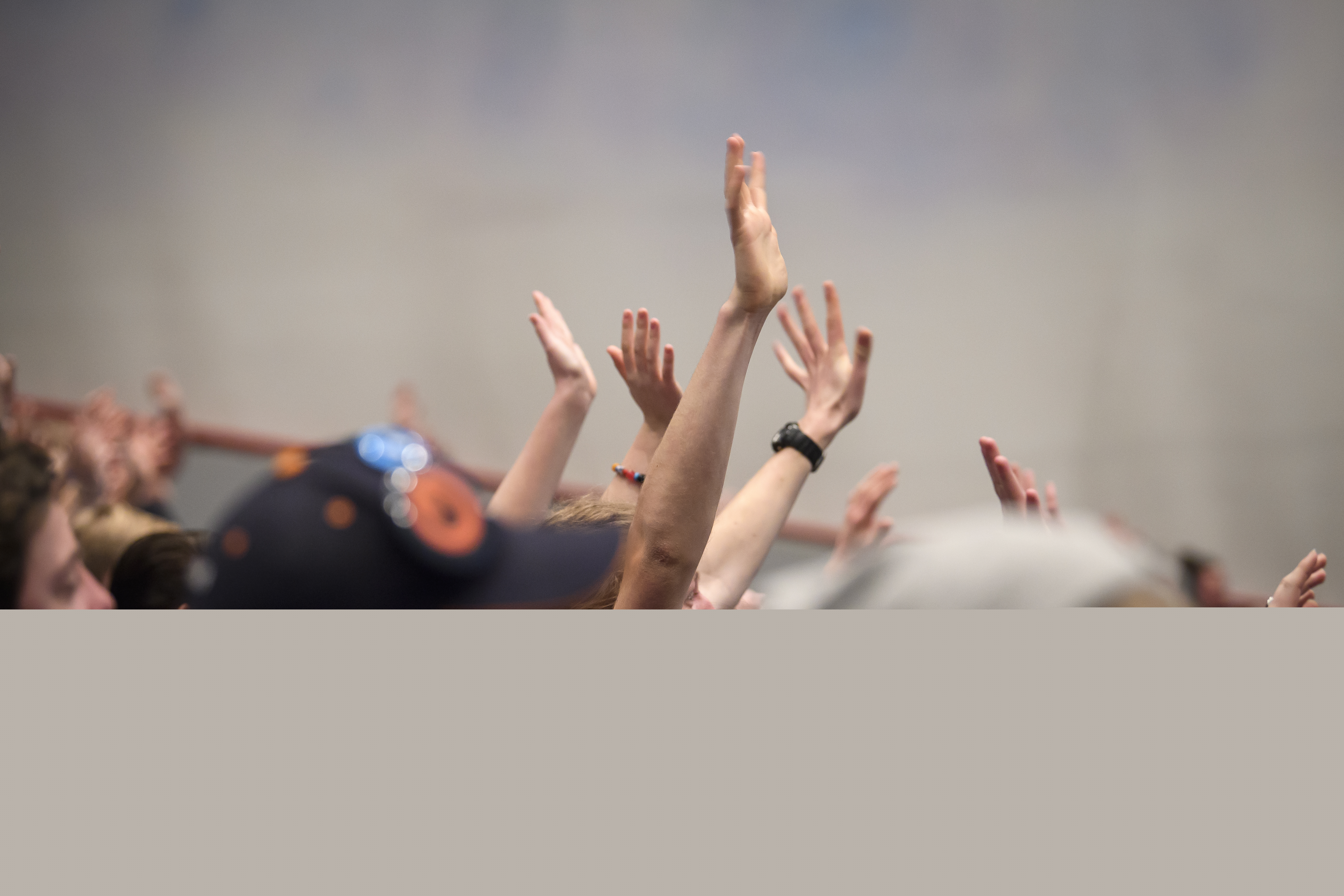 En stor grupp med ungdomar sträcker upp händerna i luften.