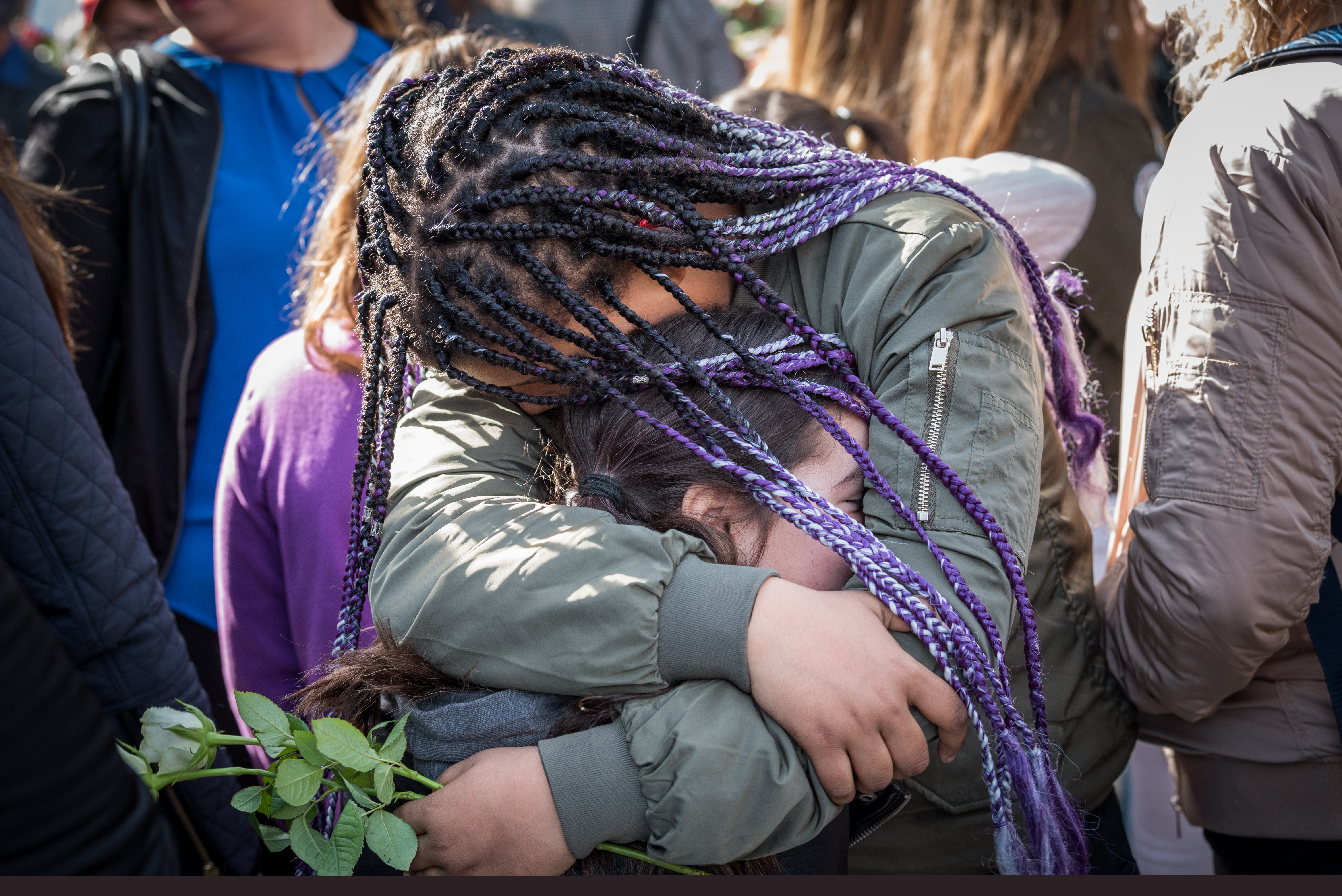 Två flickor i en folkmassa kramar om varandra hårt.