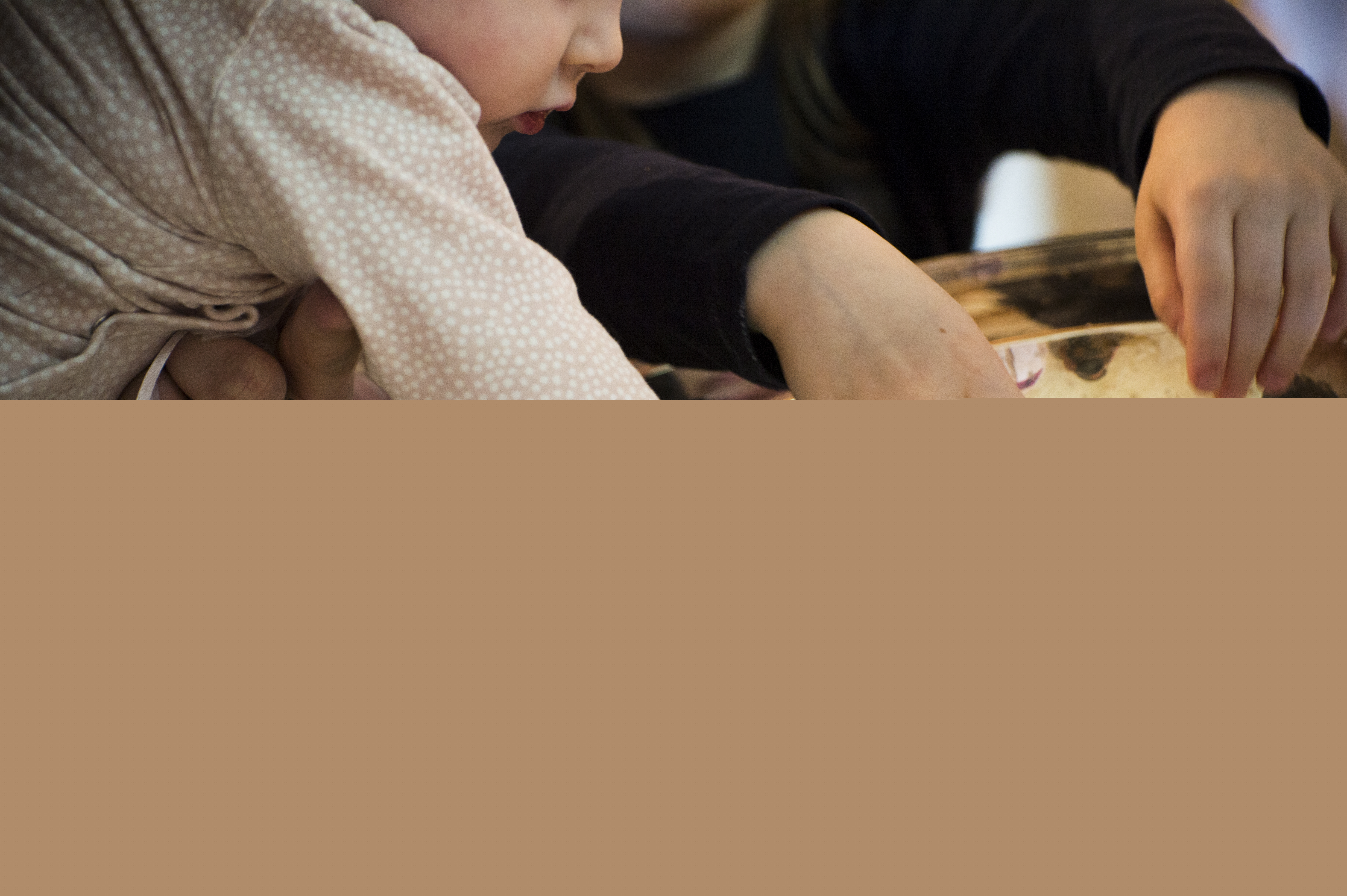 Ett litet barn doppar sina händer i en dopfunt.