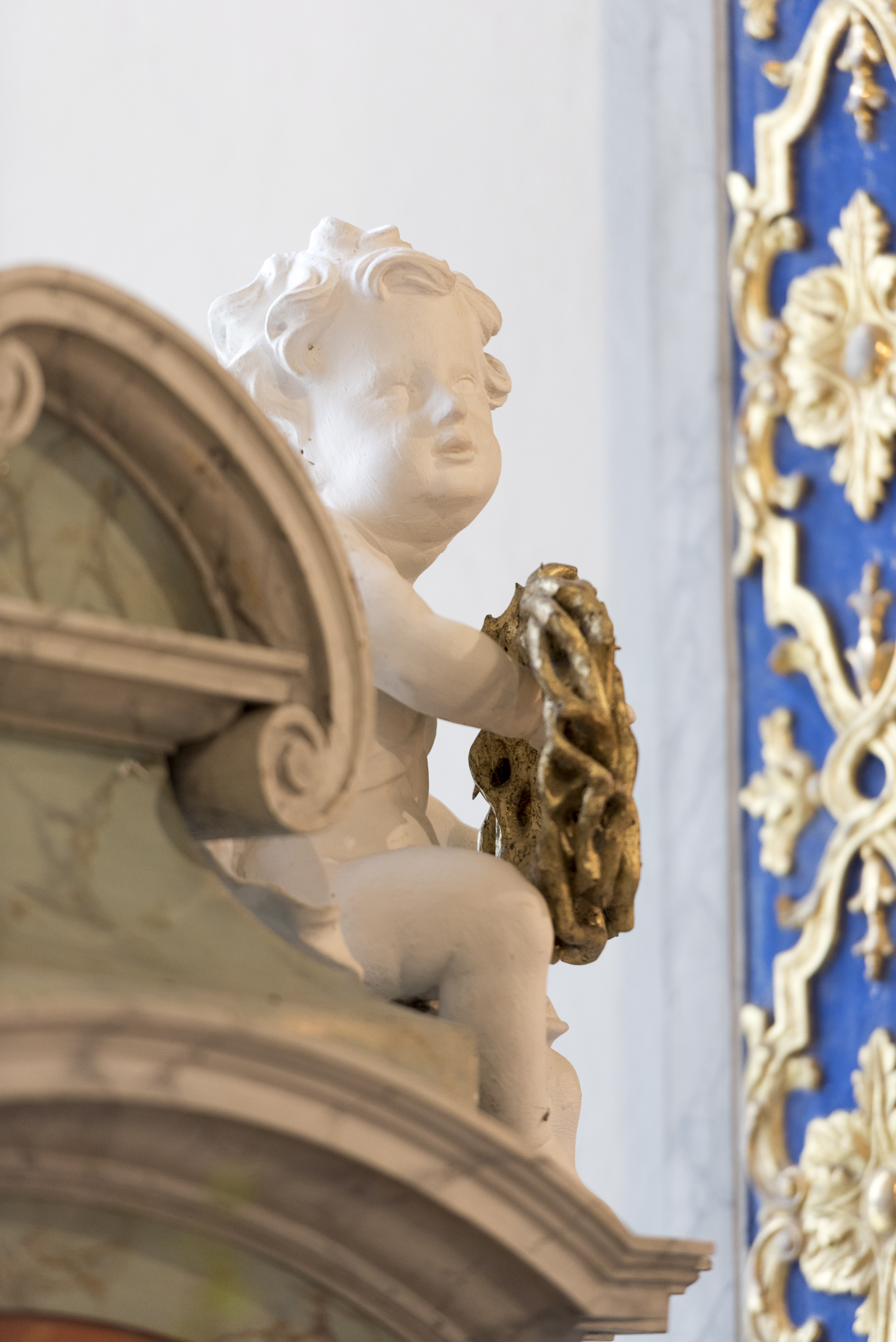 Närbild på en kerub i marmor på ett altare.