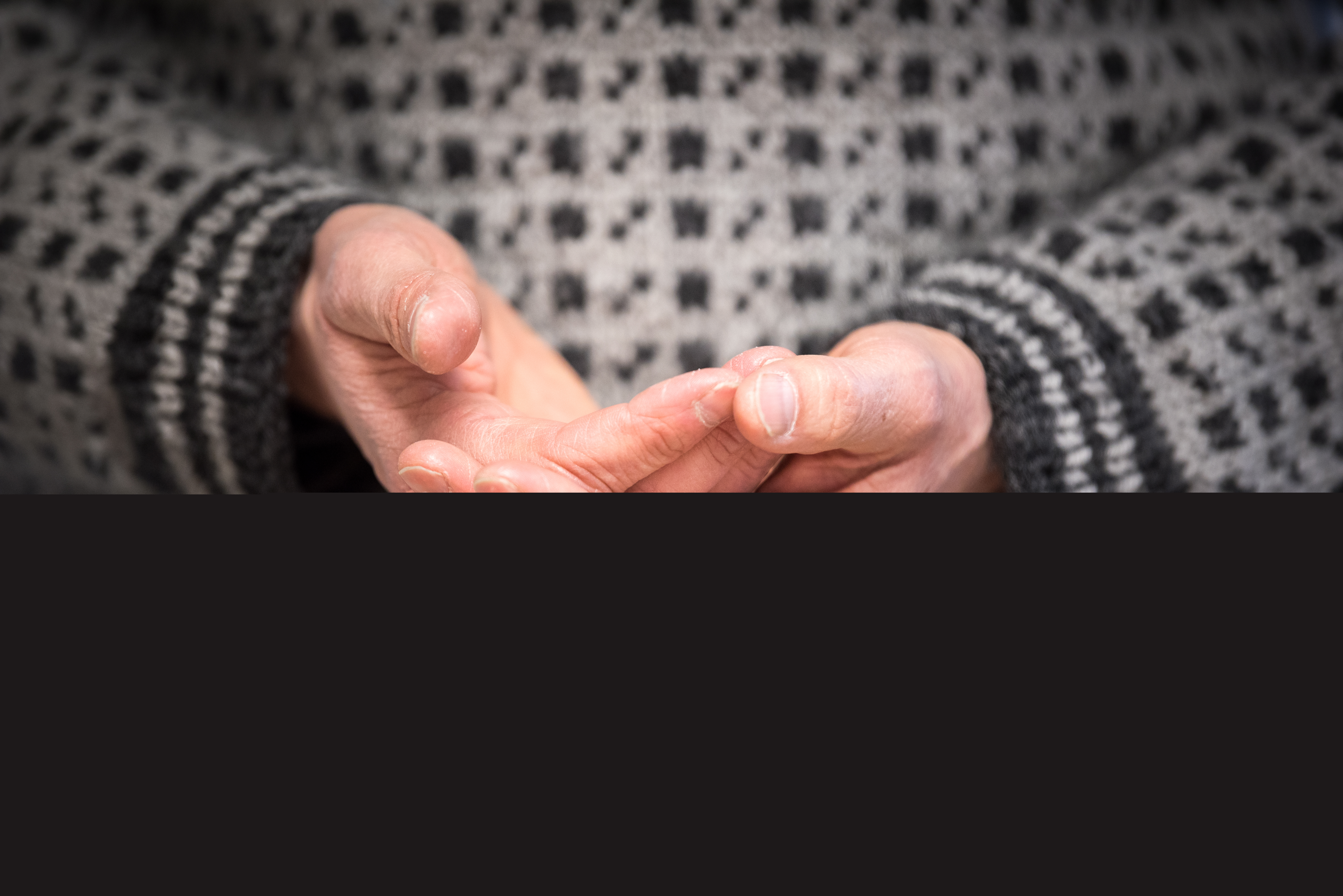 Närbild på någon i stickad fiskartröja som vilar den ena handen i den andra.