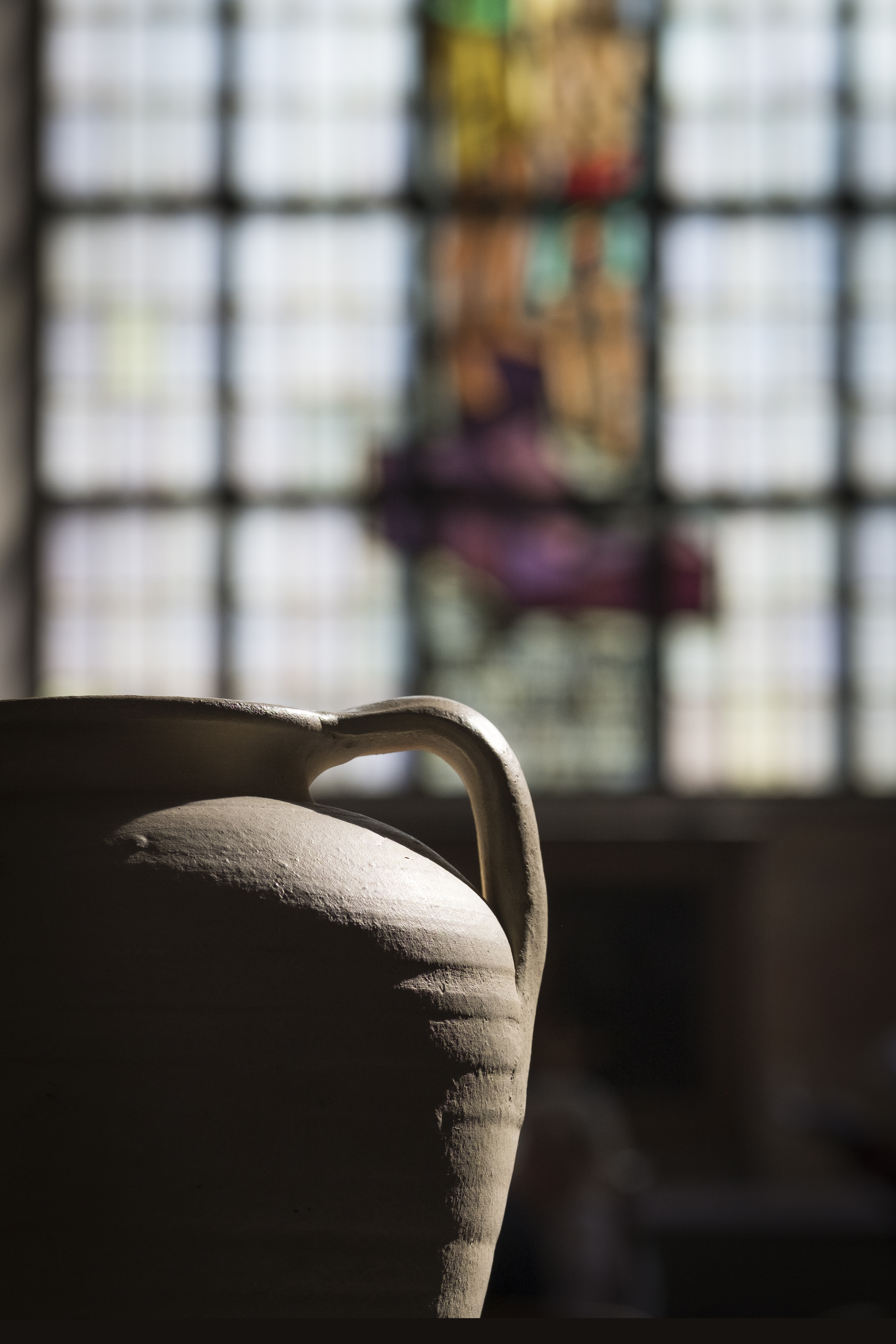 Solen lyser in på en stor kruka. Ett kyrkfönster i bakgrunden.