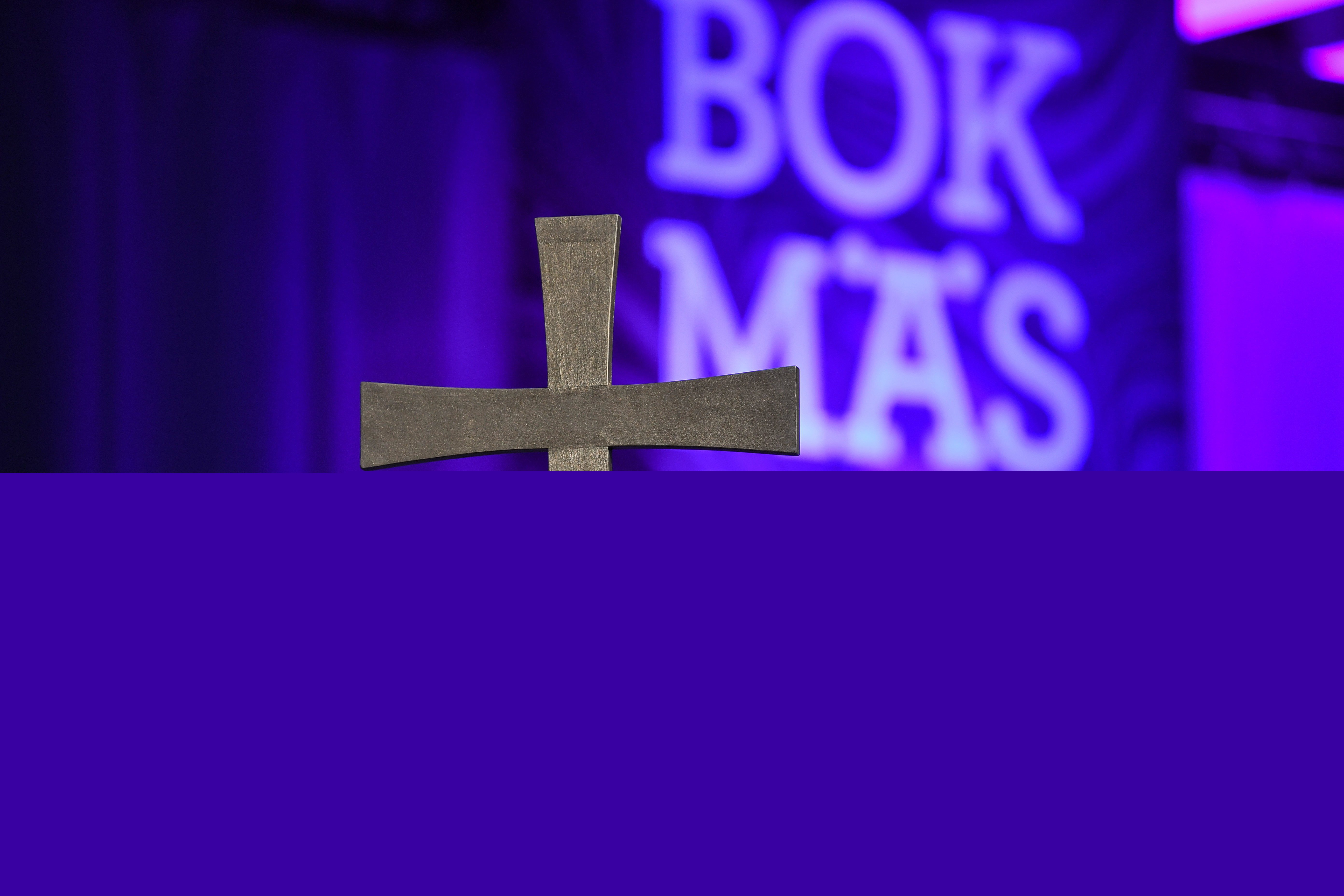 Ett järnkors och en lila skylt med texten Bokmässan syns suddigt i bakgrunden.