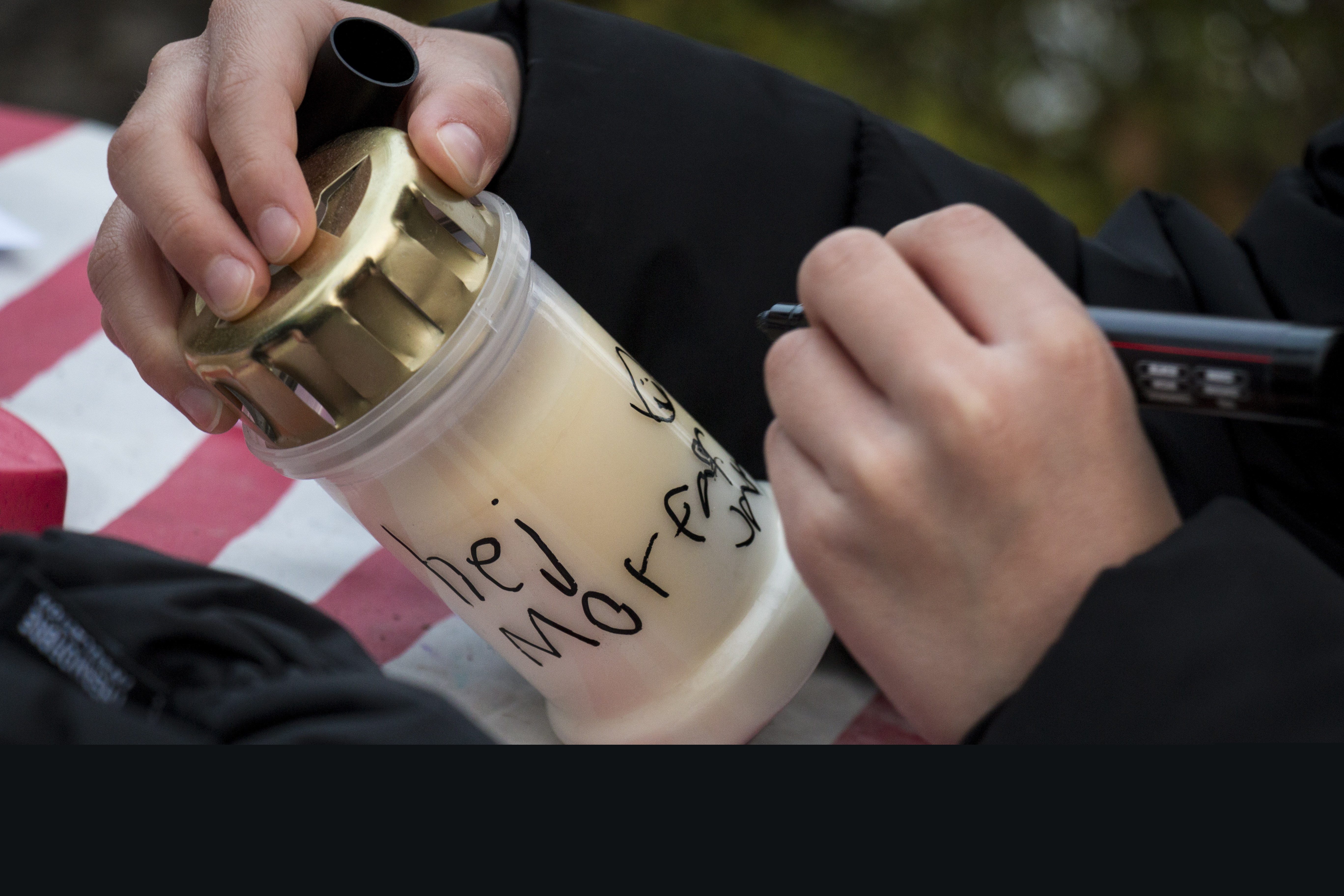 Ett barn skriver en hälsning till sin morfar på ett gravljus.