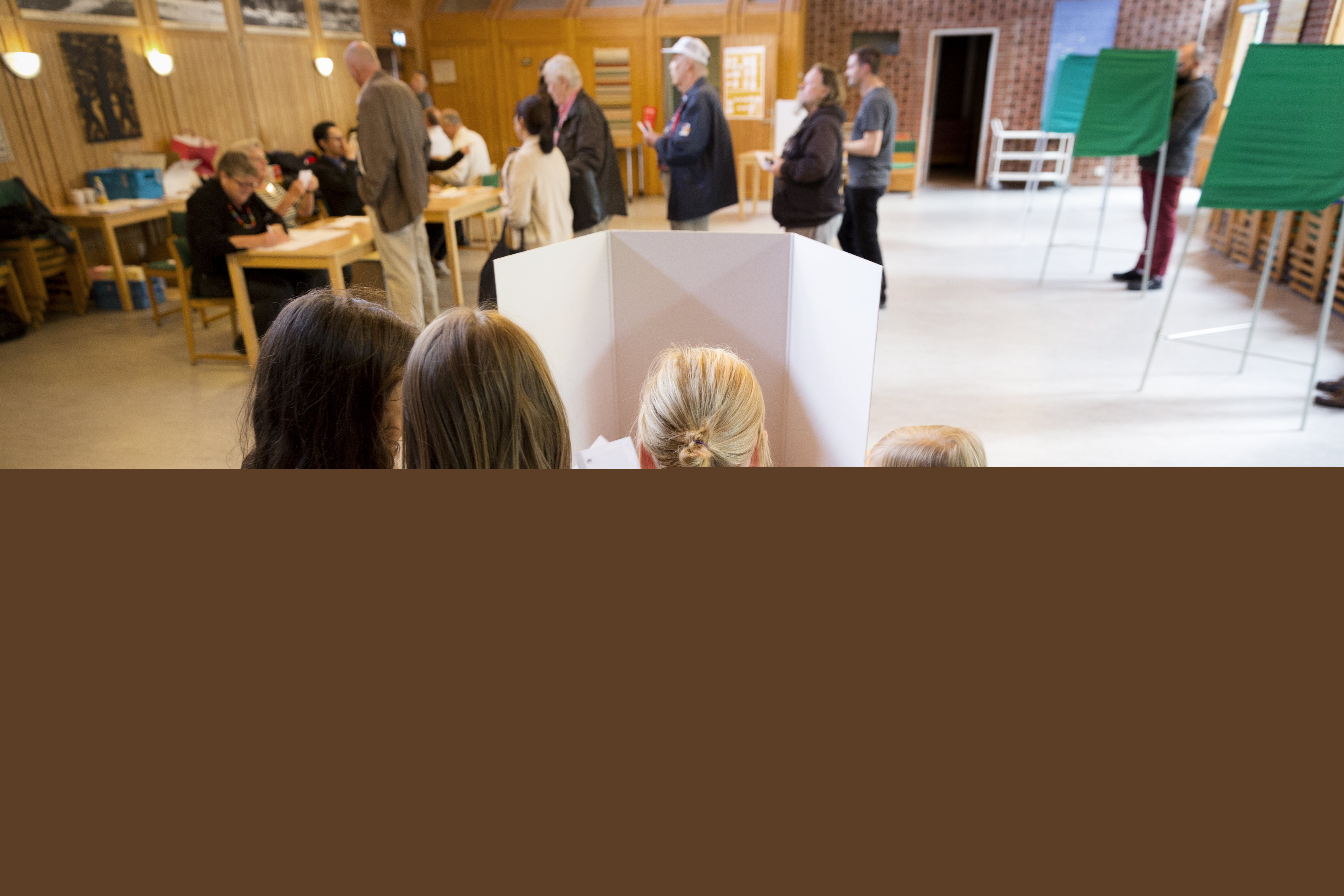 Tre små flickor står runt sin mamma i ett röstbås.