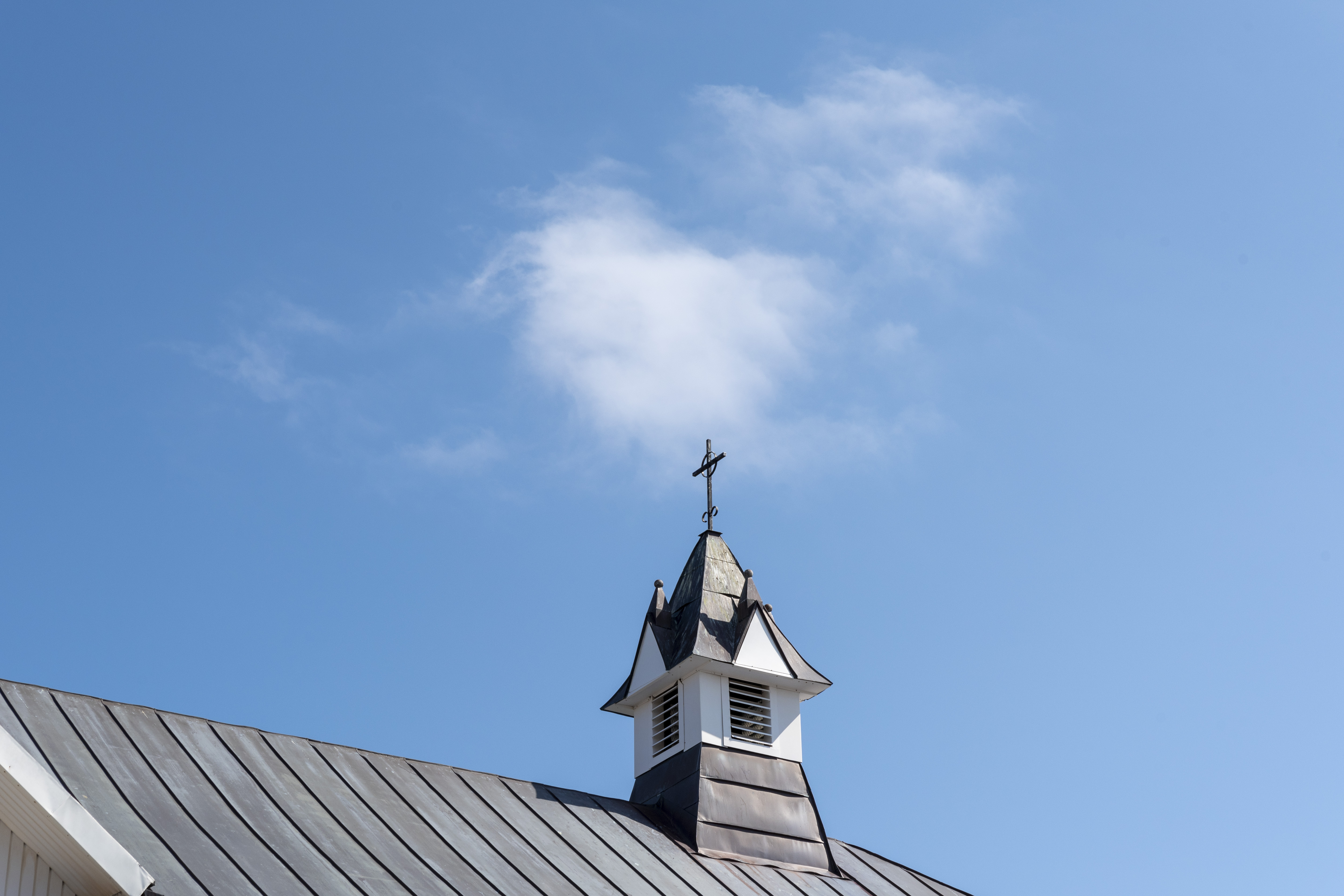 Ett litet torn på ett kyrktak mot blå himmel.