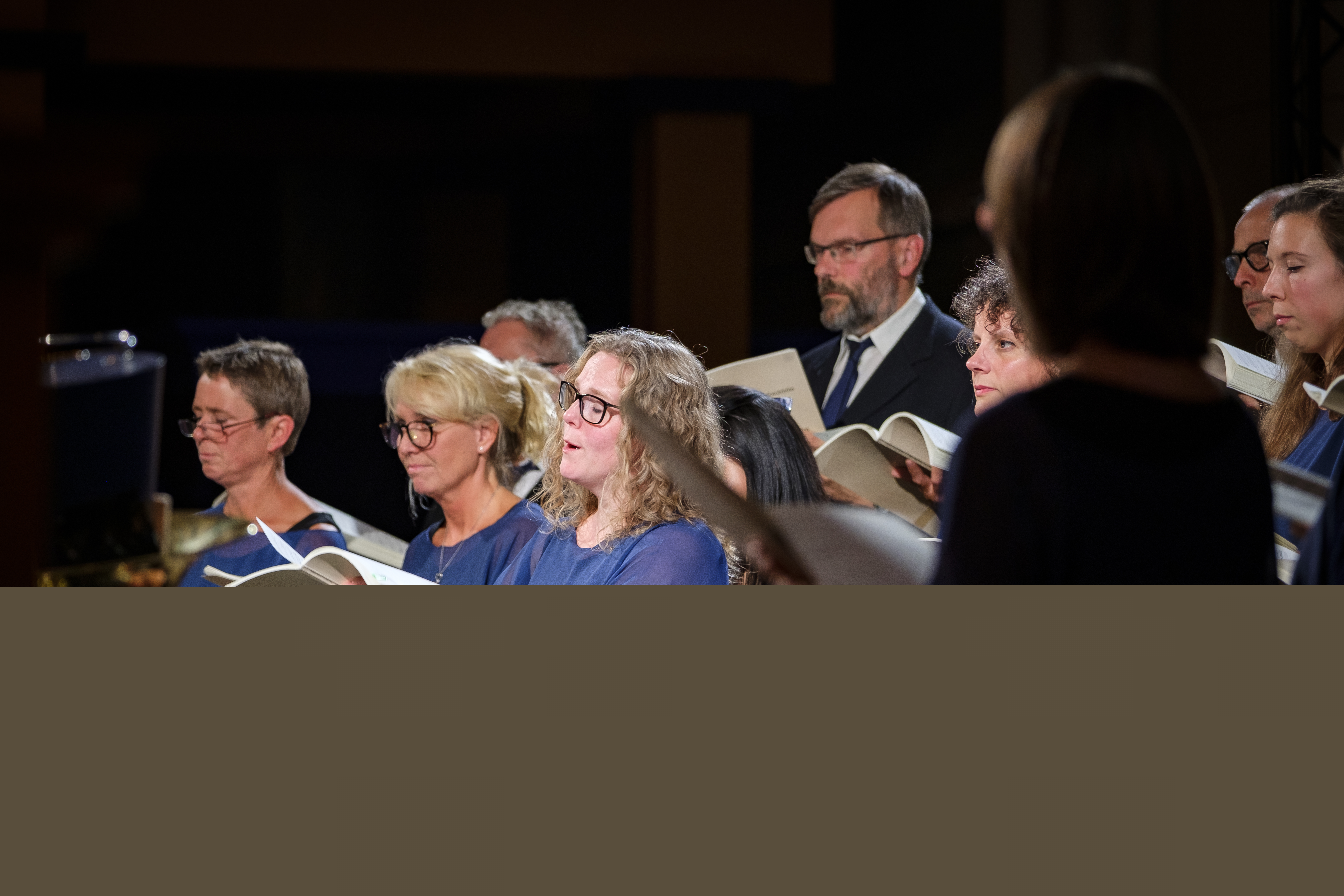 En blandad kyrkokör i matchande blå färger sjunger.
