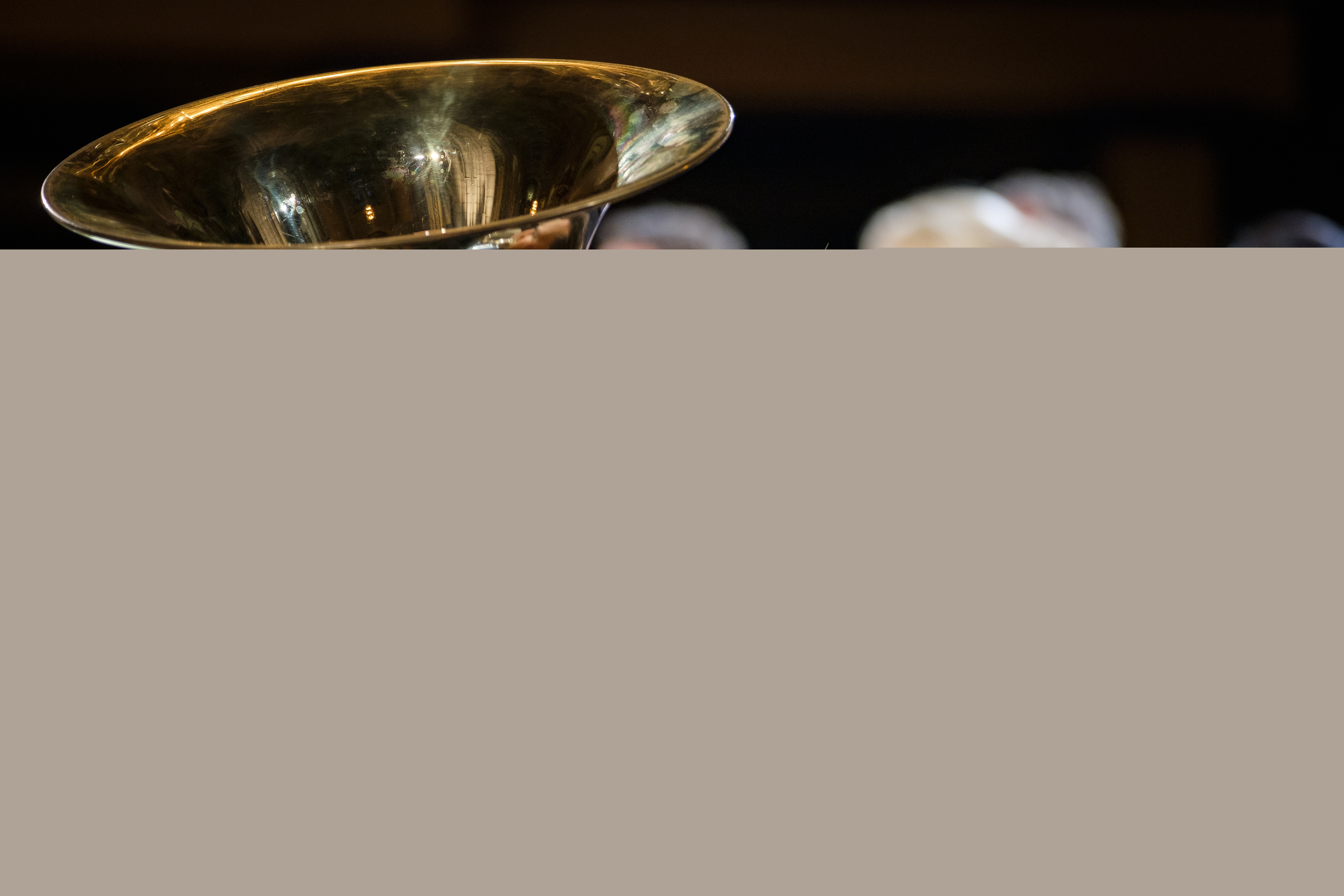 En man i en orkester spelar bastuba. En kör syns i bakgrunden.