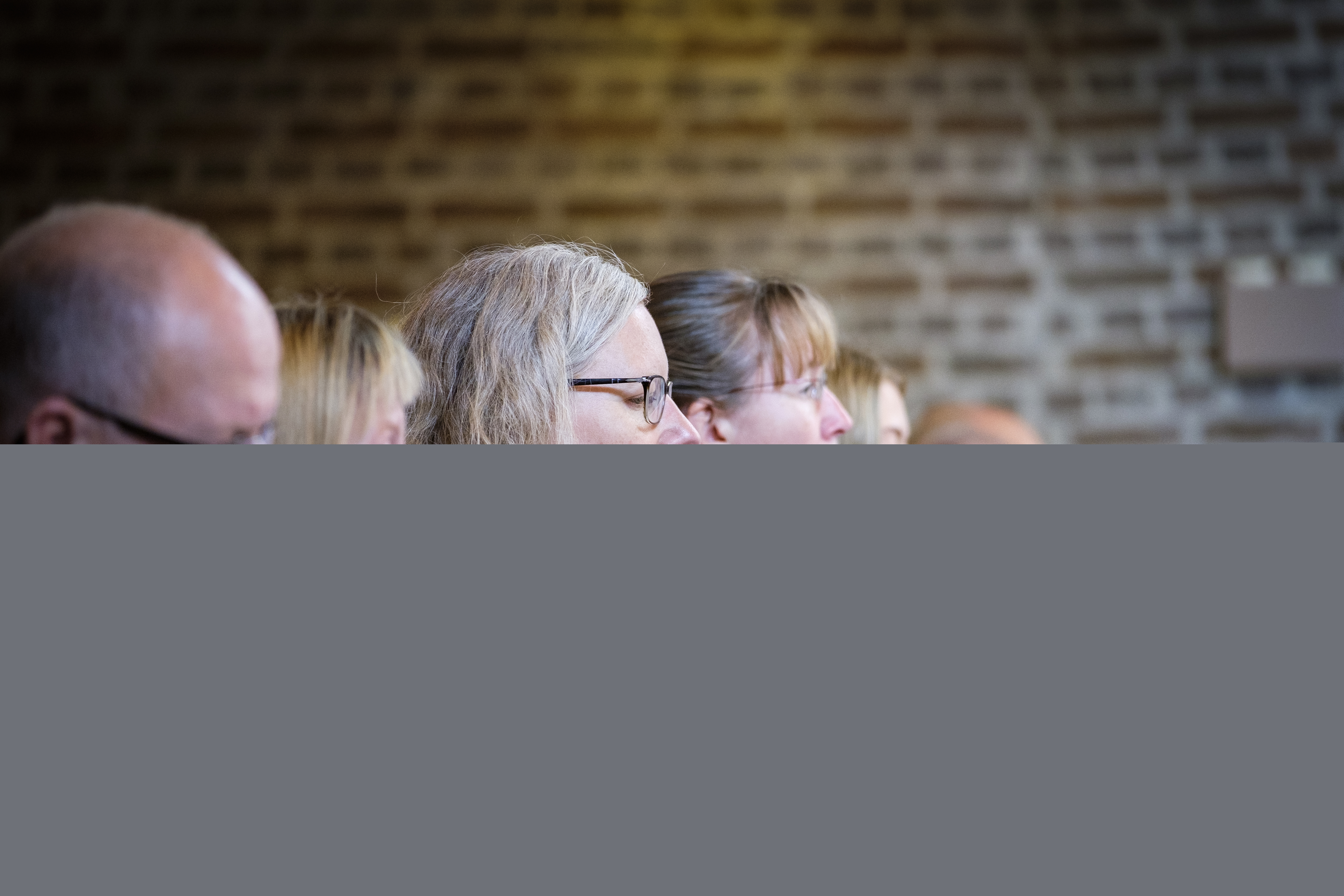 En rad människor står och sjunger från sånghäften.