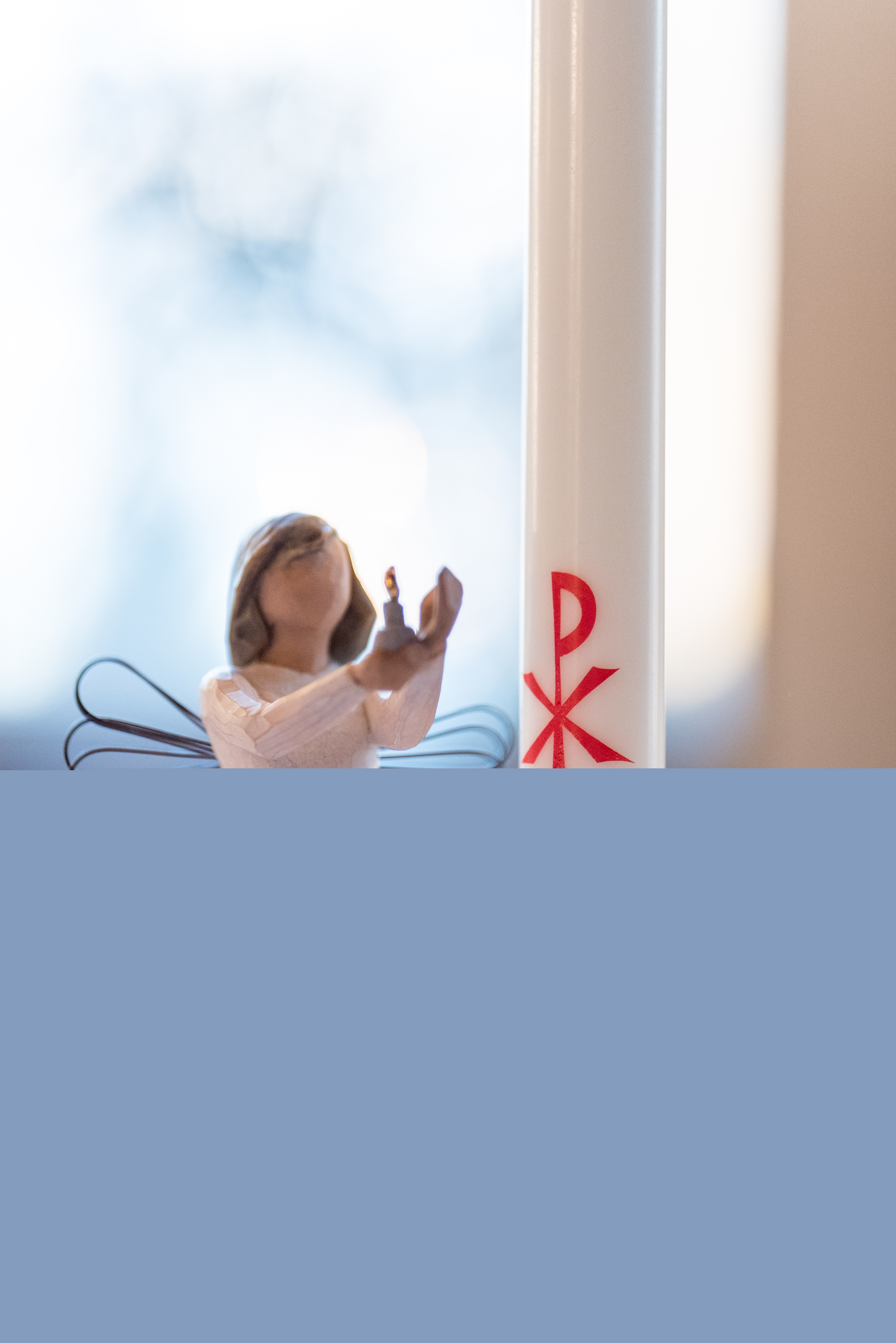 En prydnadsängel står bredvid ett dopljus.