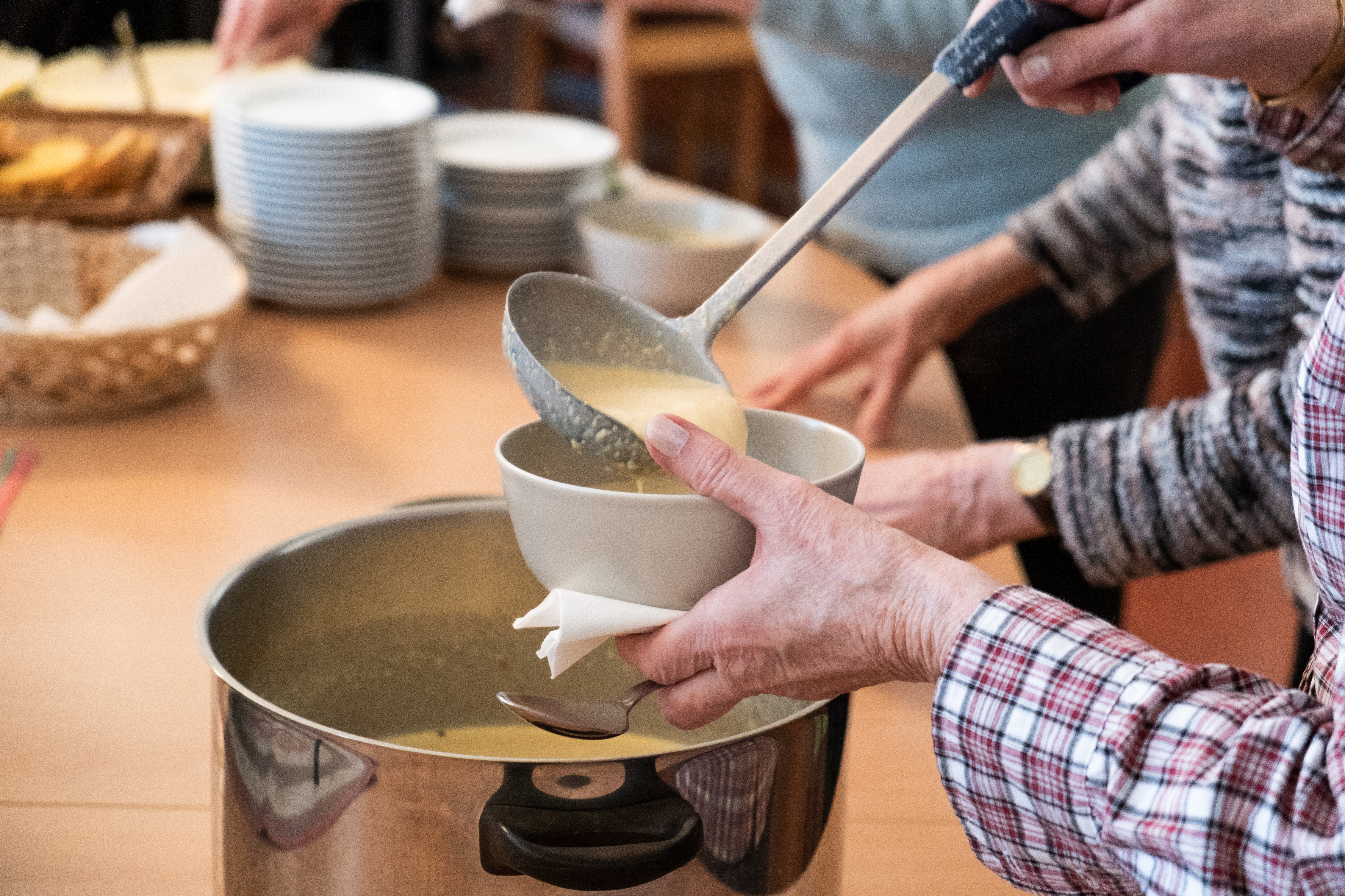 Någon slevar upp soppa i en skål.