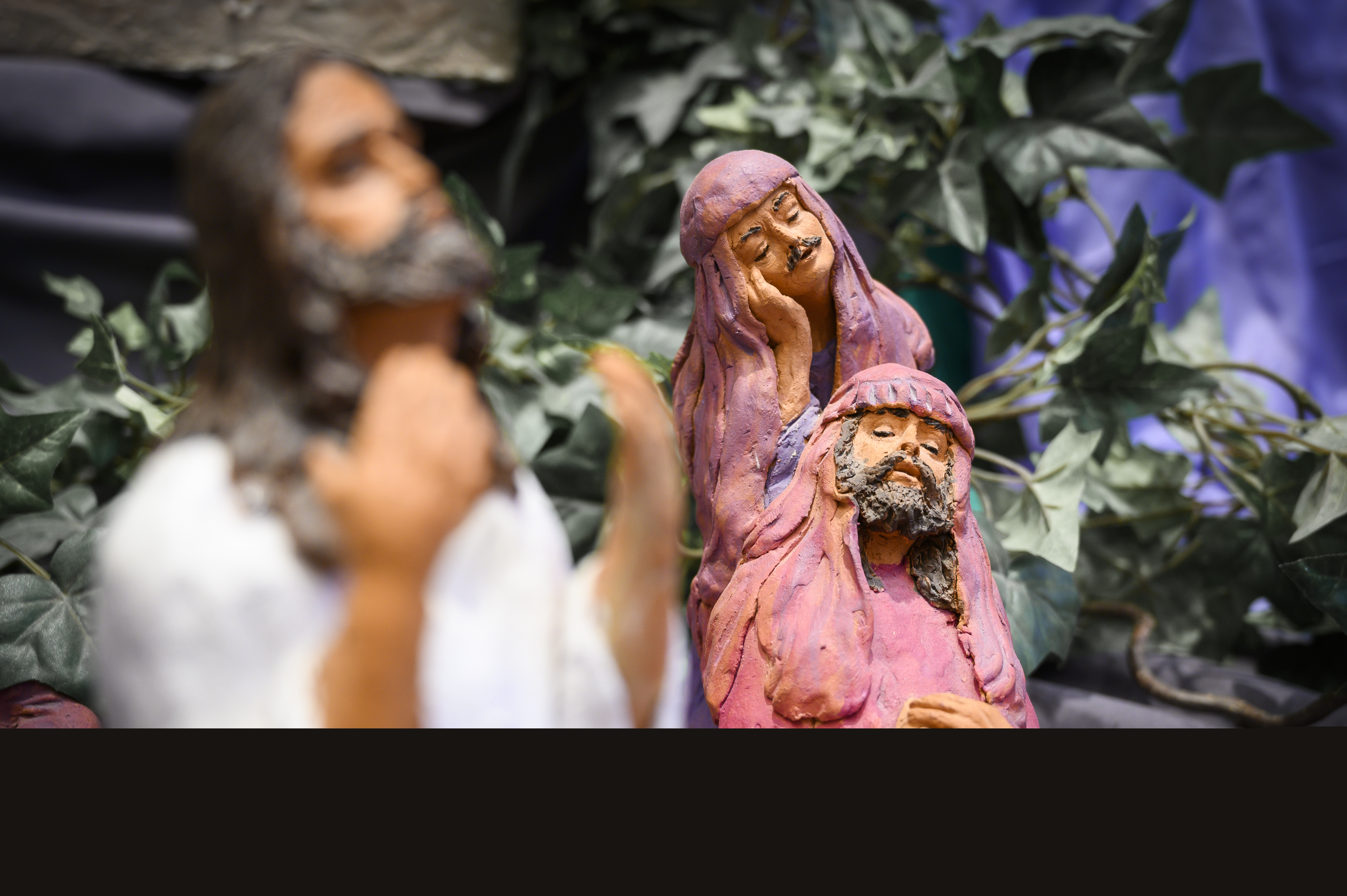 Modell med Jesus och två män i ljusröda kåpor och huvuddukar.