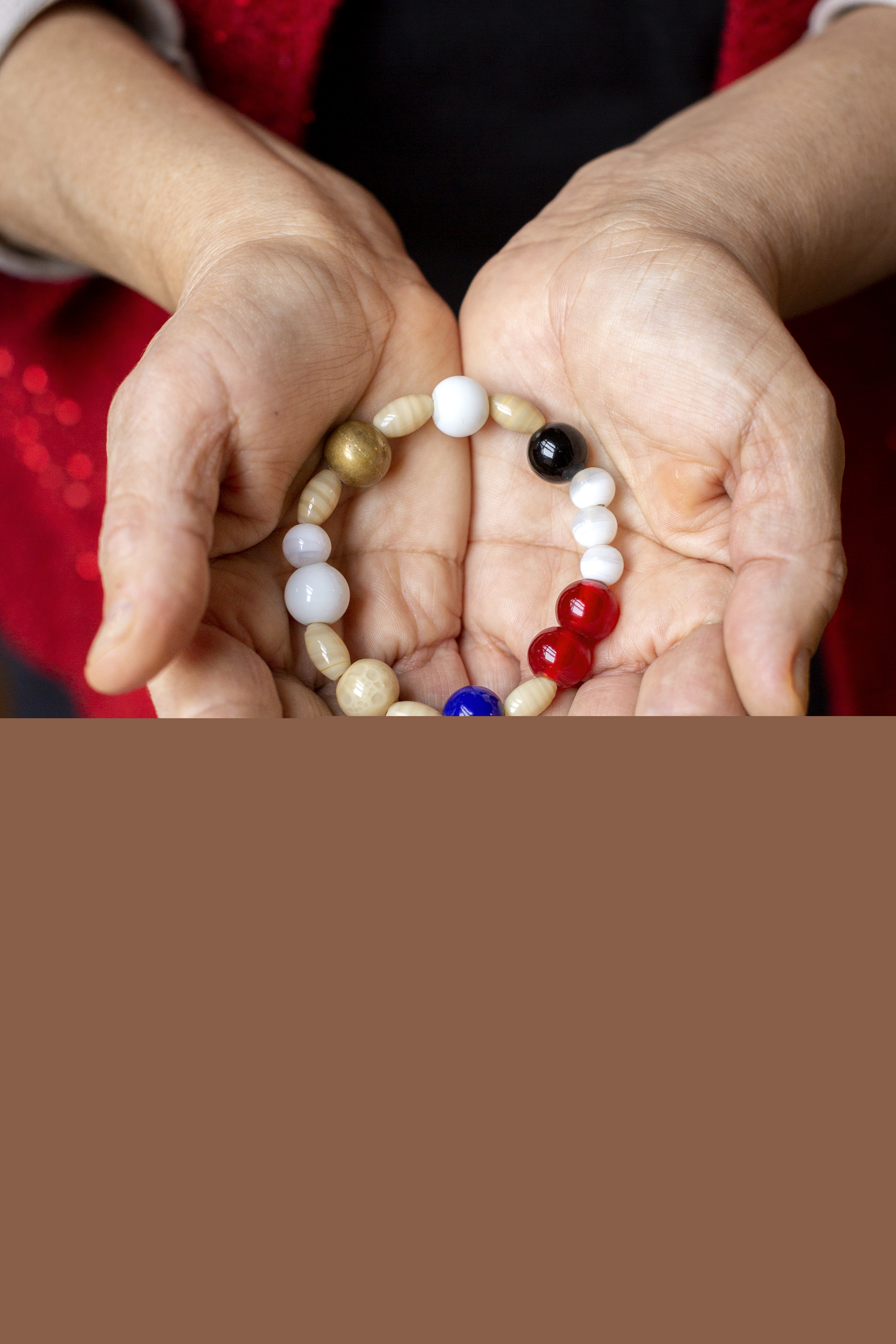 En person håller ett armband av olika pärlor i sina kupade händer.