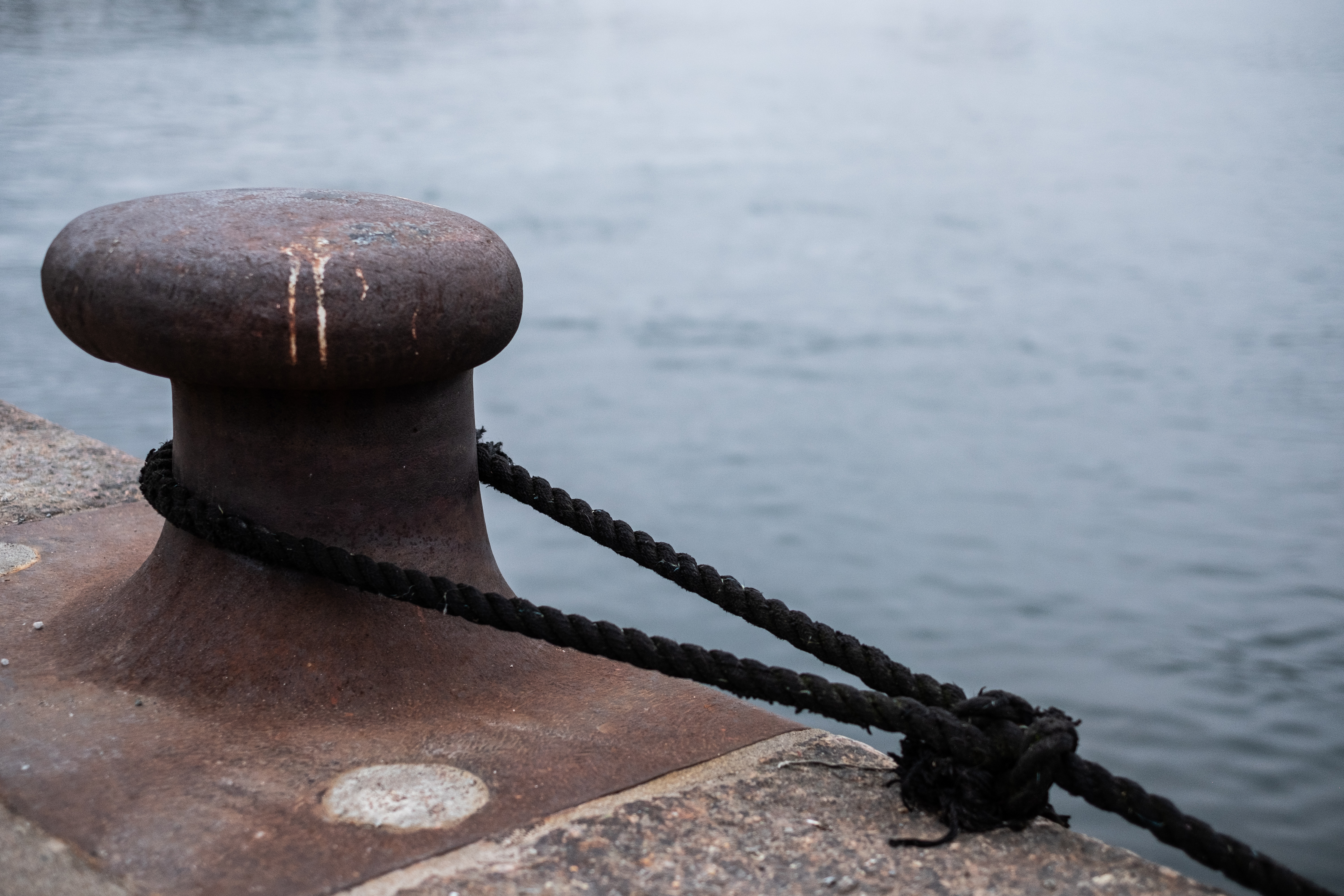 En svart tross har lagts runt en pollare vid kajkanten.