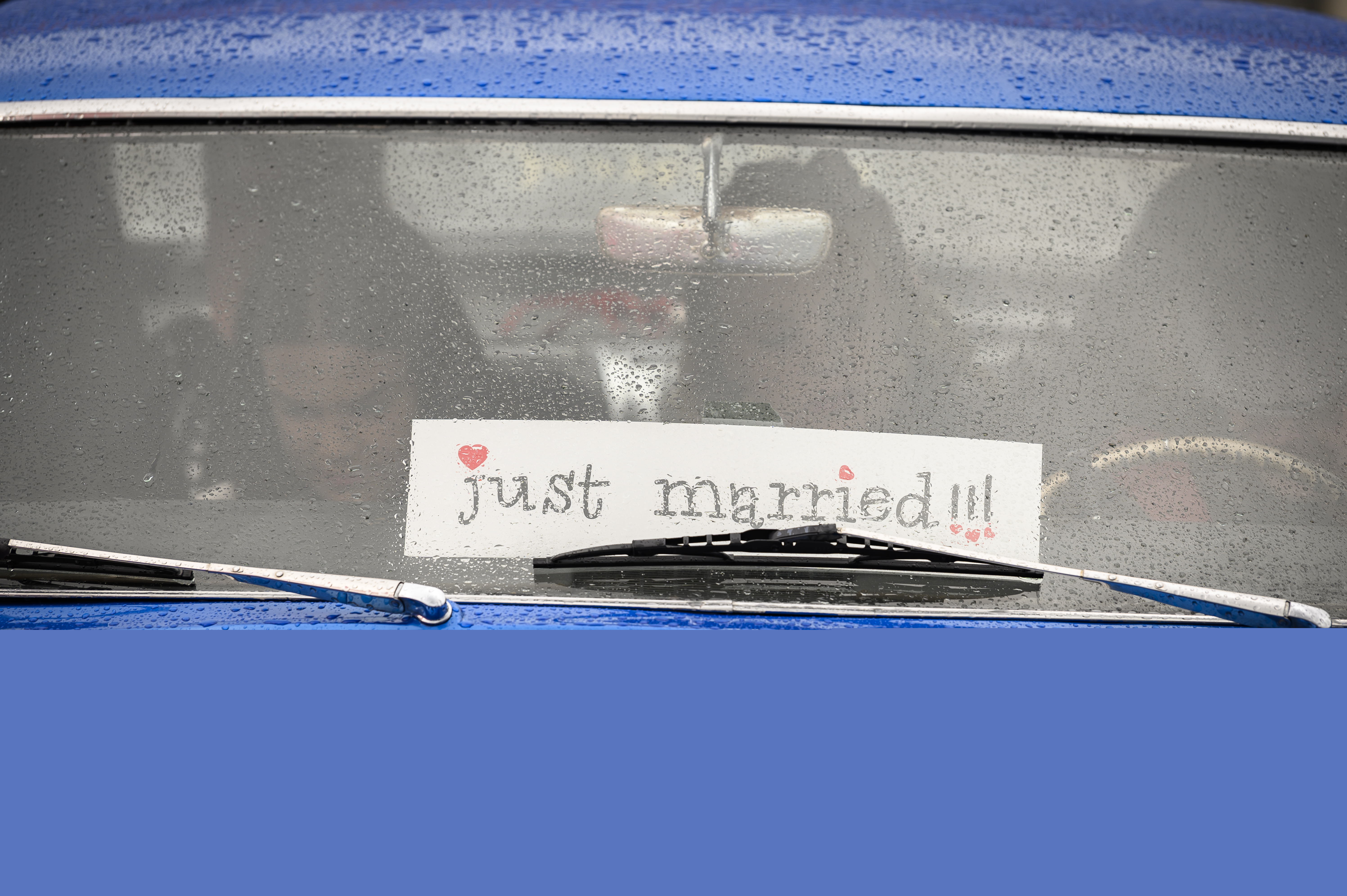 En blå bil med en skylt med texten Just married i framrutan.