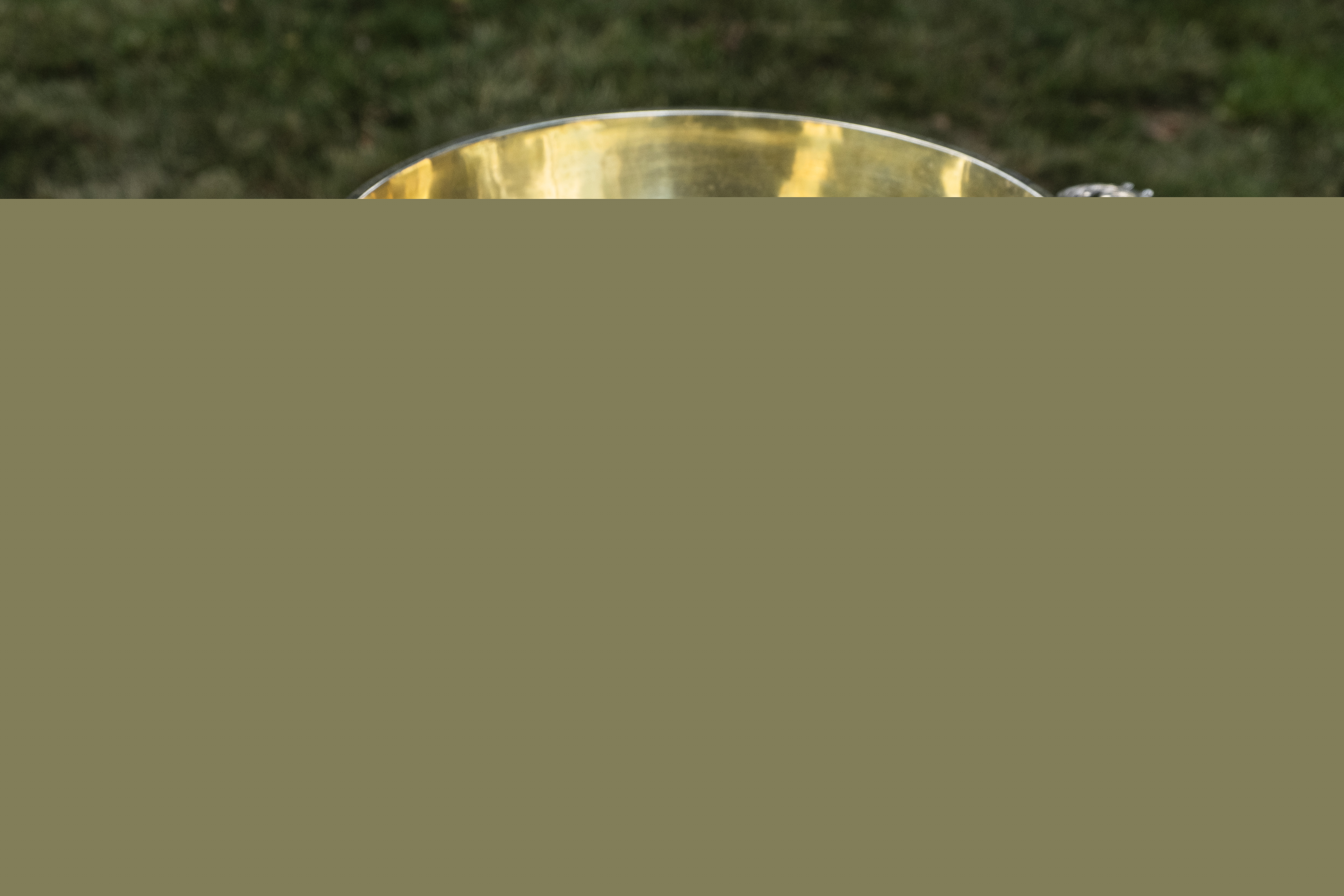 En dopfunt står utomhus på ett bord med en broderad duk.