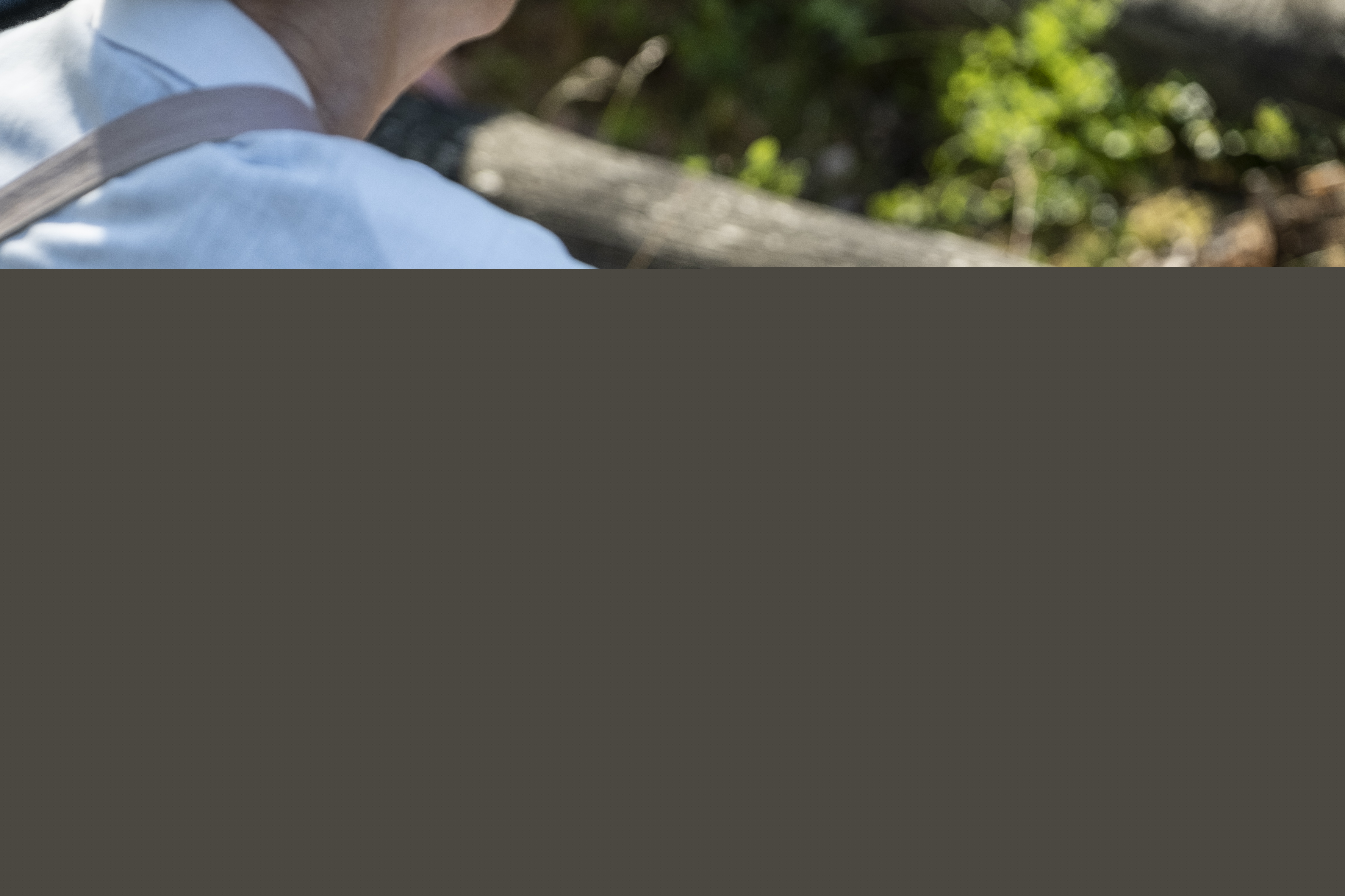 En person i skjorta sitter i skogen.