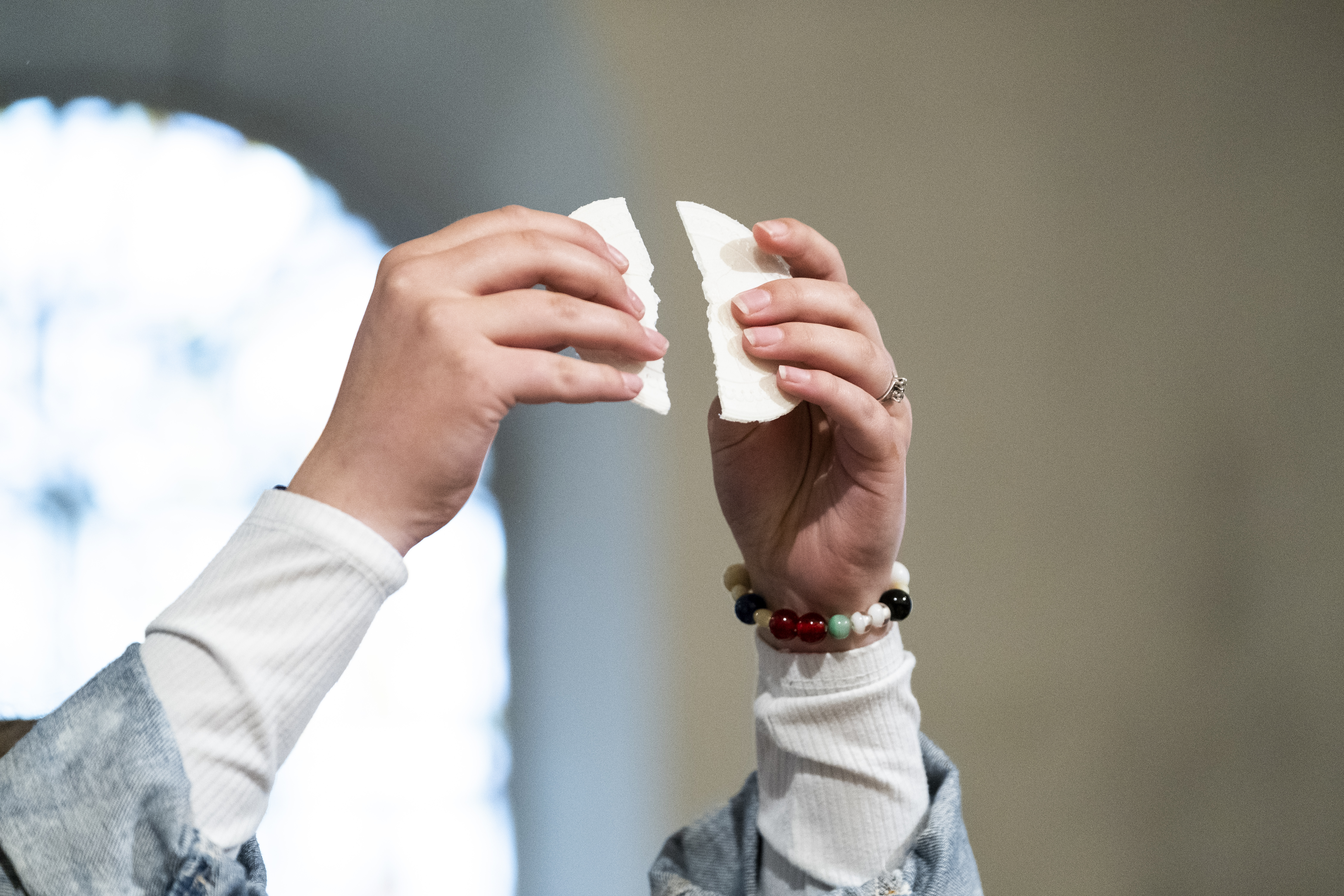 Någon håller upp händerna och bryter en oblat.