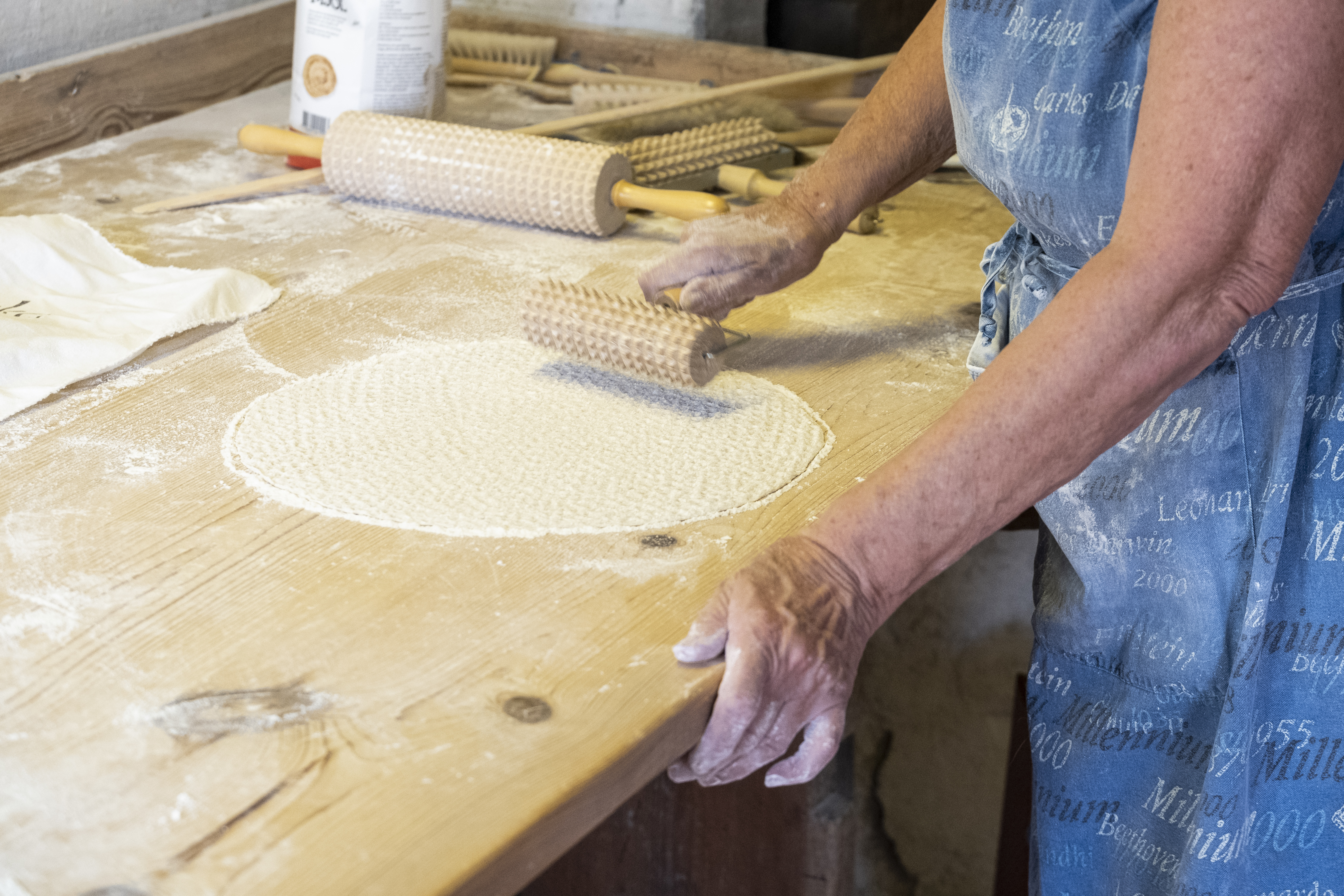 Någon bakar knäckebröd och gör mönster i degen.