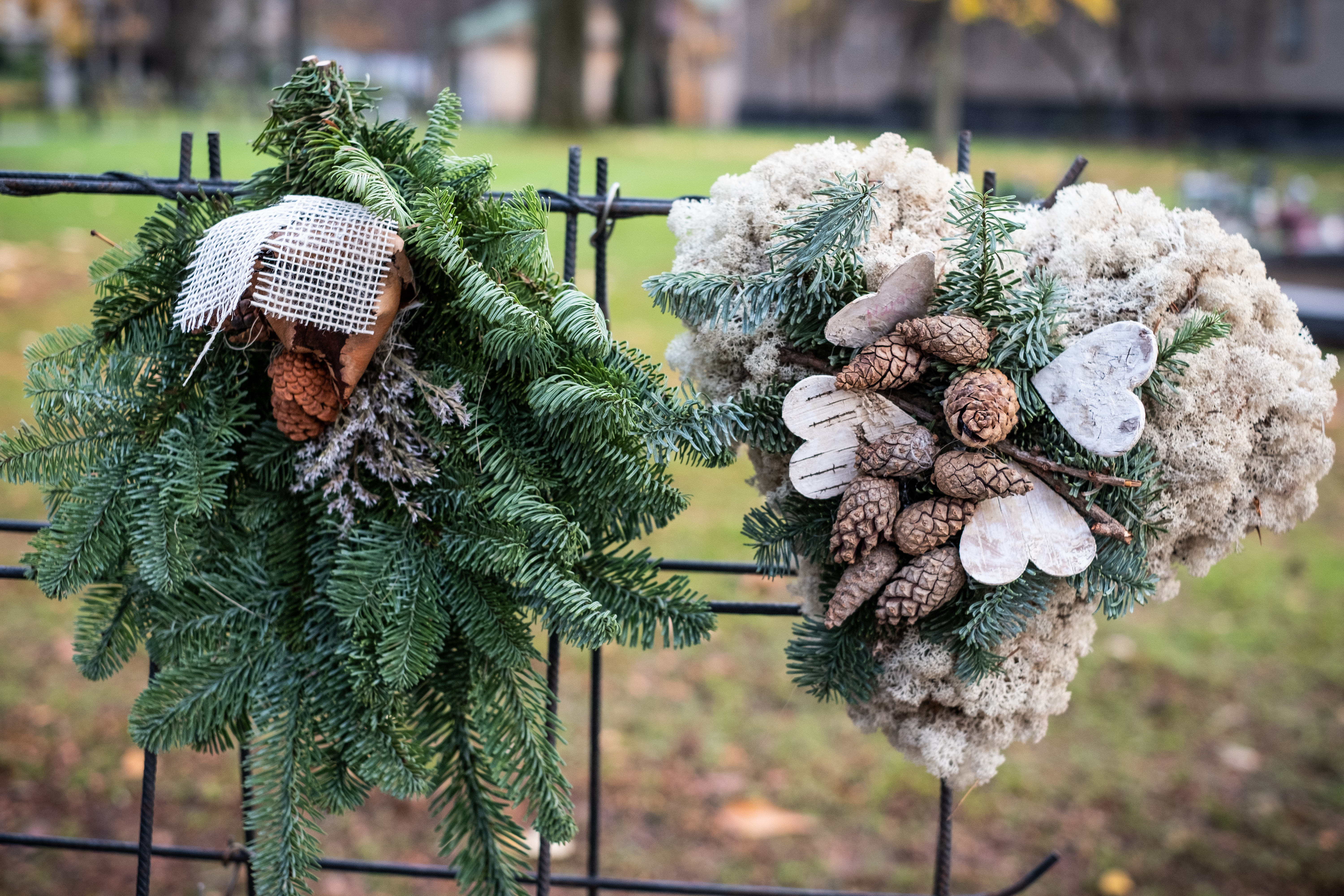 Två gravkransar hänger på en ställning på en kyrkogård.