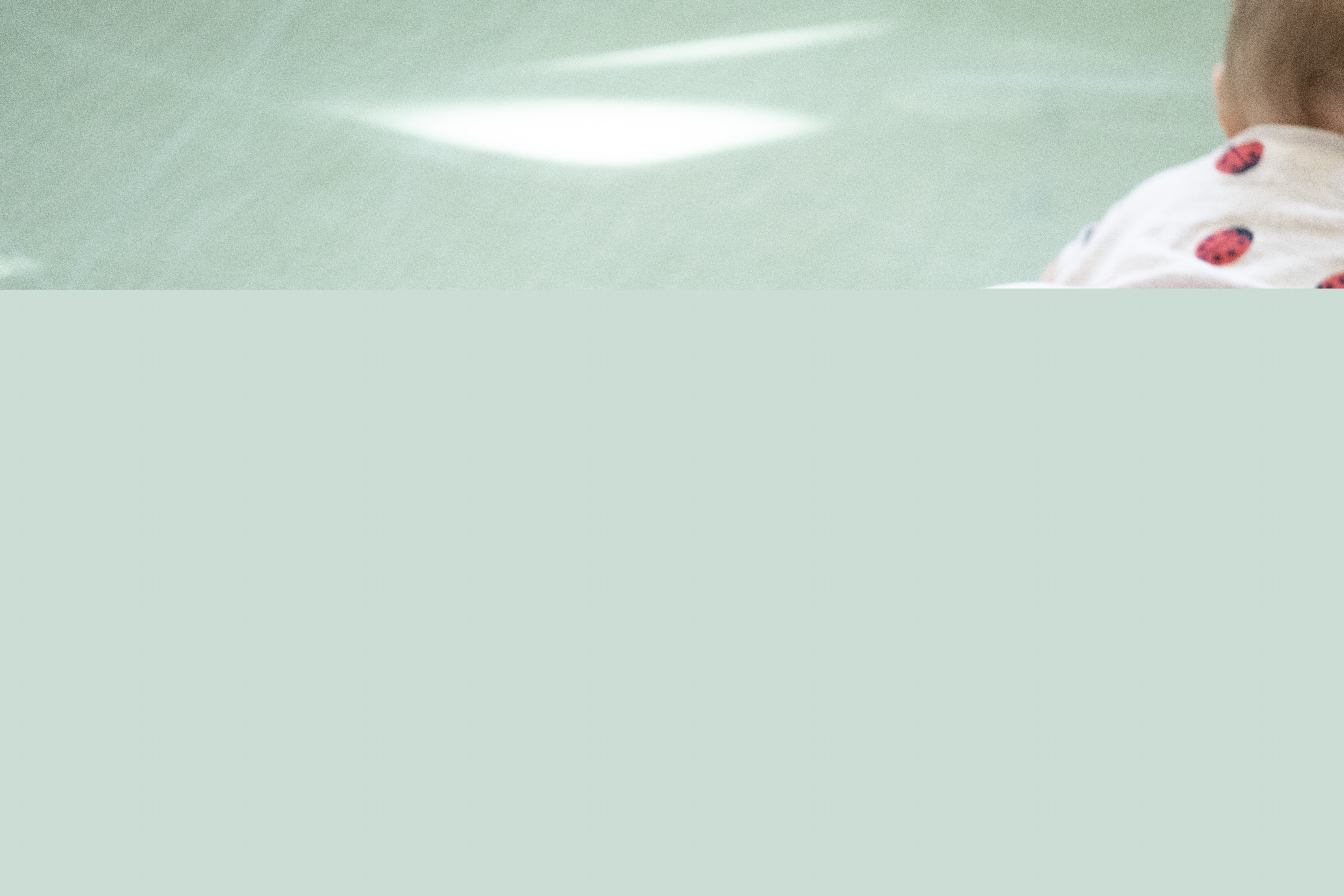 En bebis med nyckelpigor på kläderna ligger på mage på golvet.