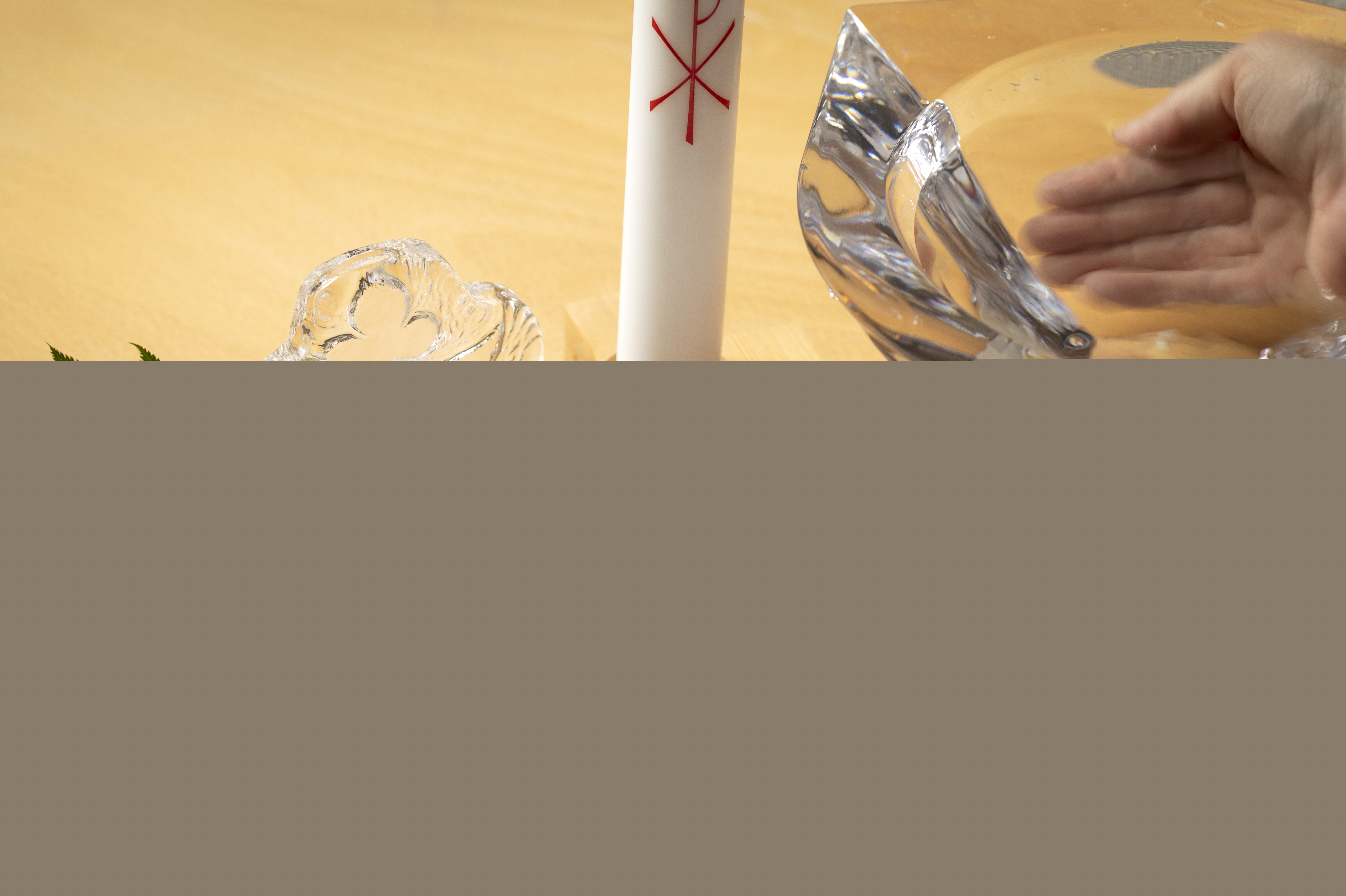 Bredvid en glasskål och ett dopljus ligger en uppslagen bok med rubriken Dop i krissituation.