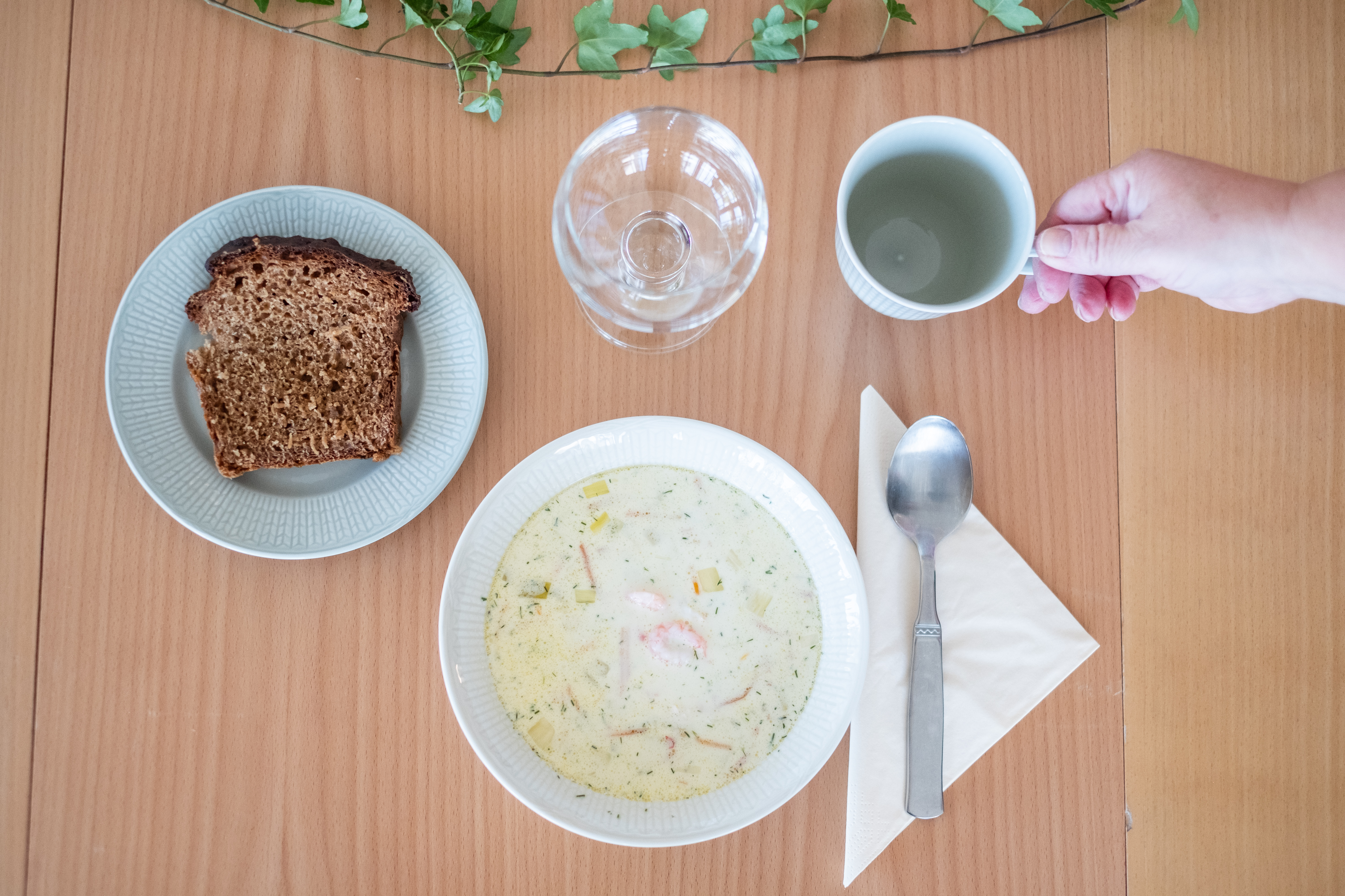 En skål soppa och en brödbit står framdukat på ett bord.