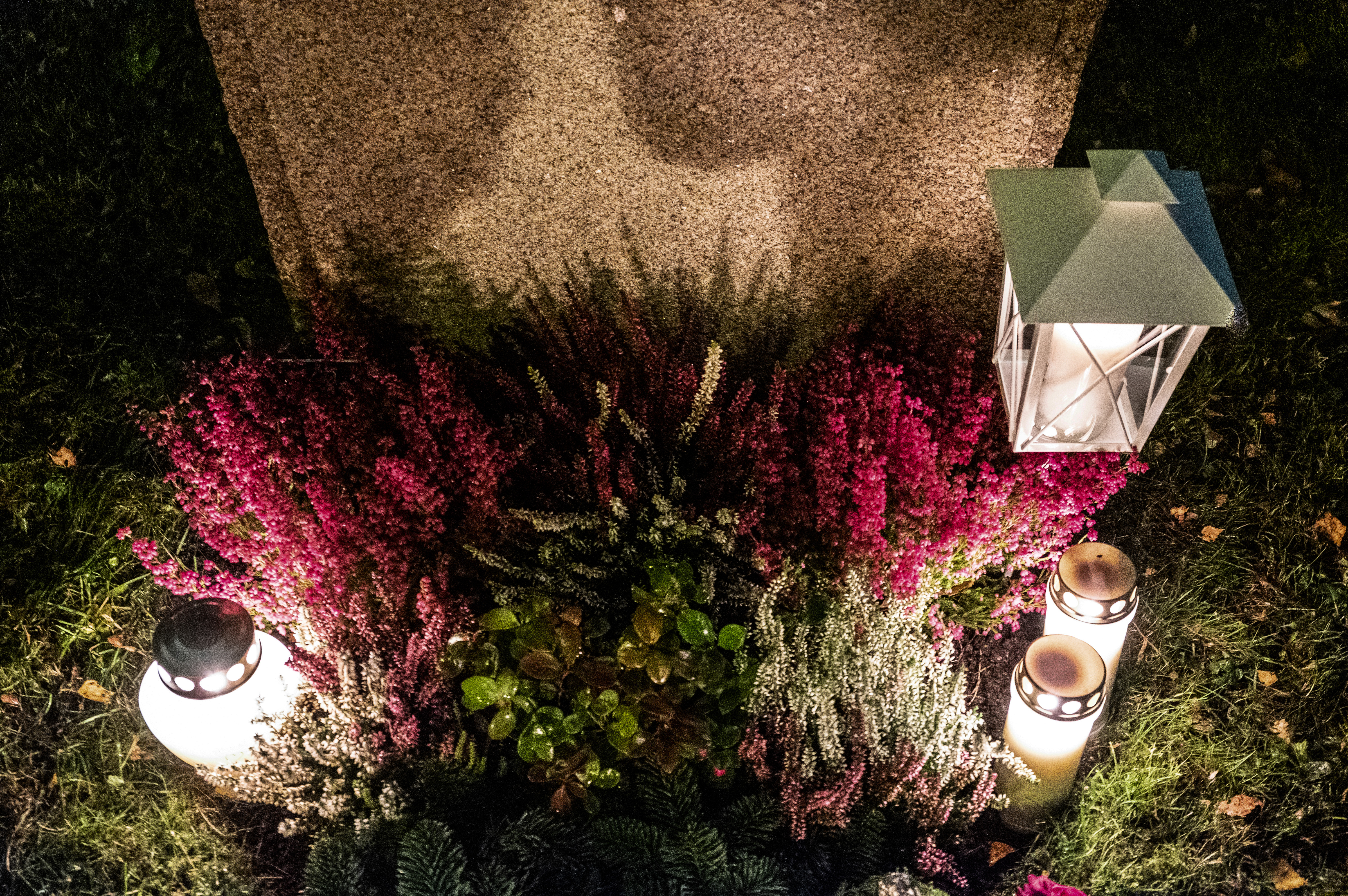 En grav har smyckats med tända ljuslyktor och ljung.