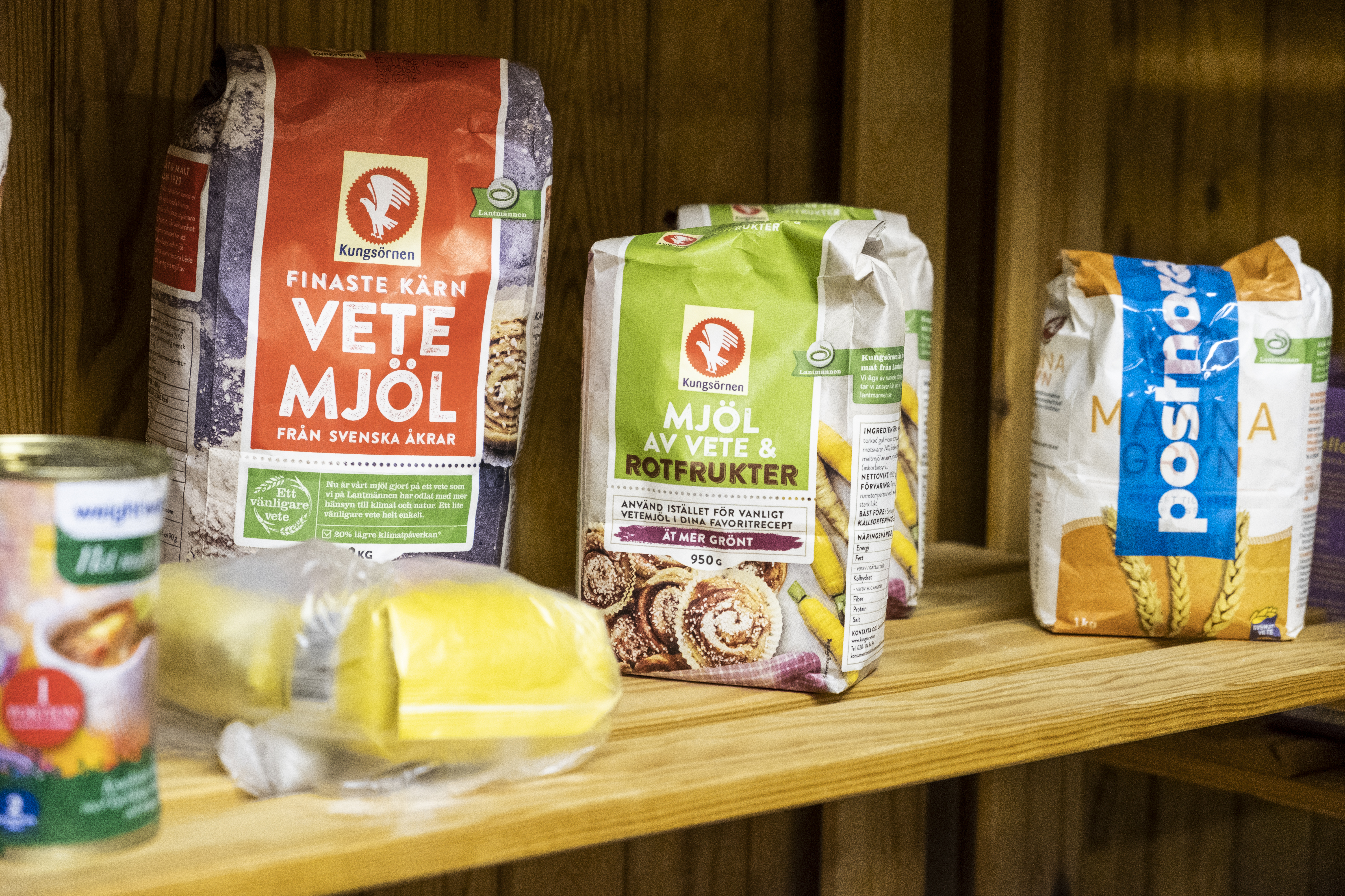 Några olika sorters mjöl och en konservburk på en trähylla.