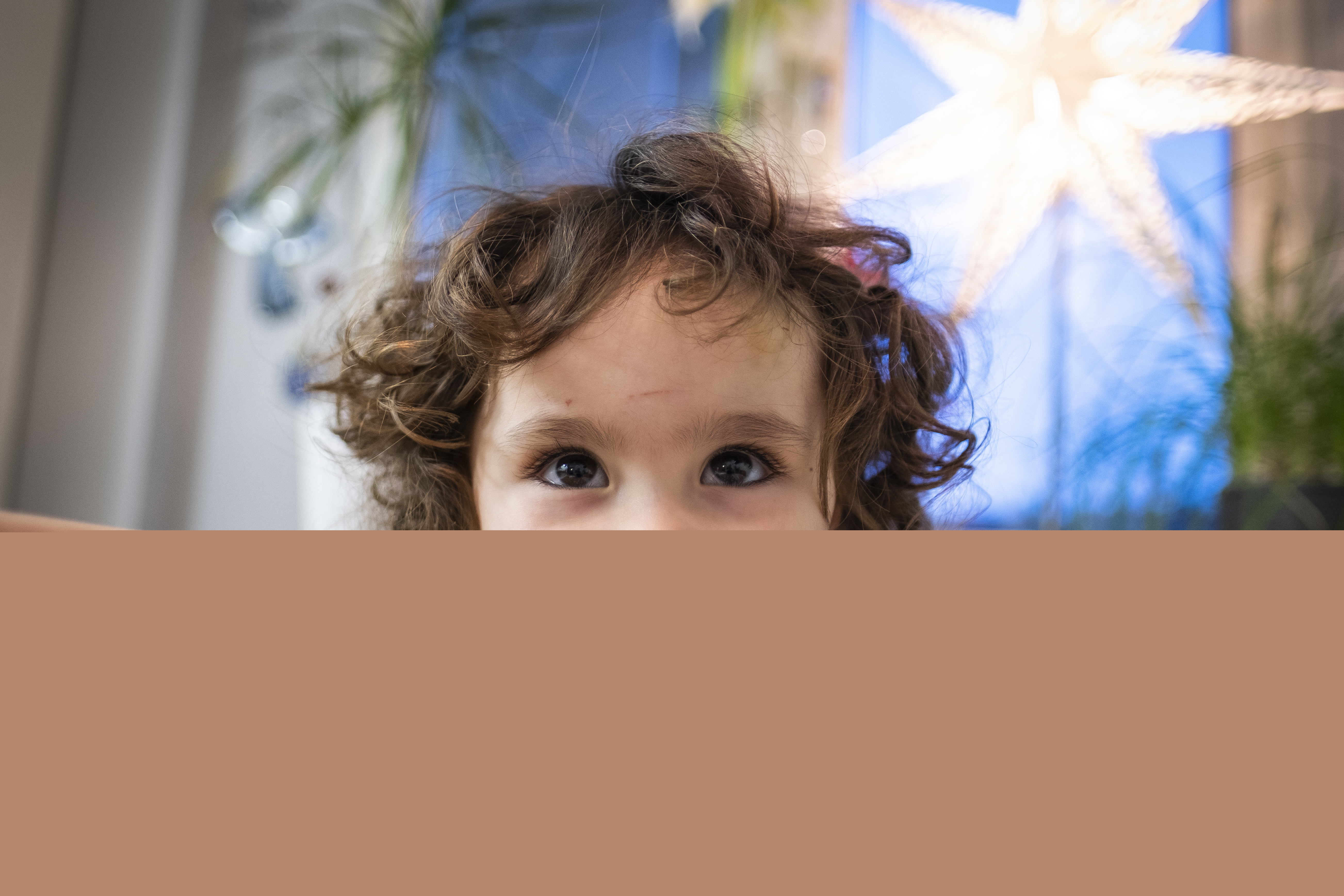 Ett litet barn med krulligt hår tittar nyfiket mot kameran.