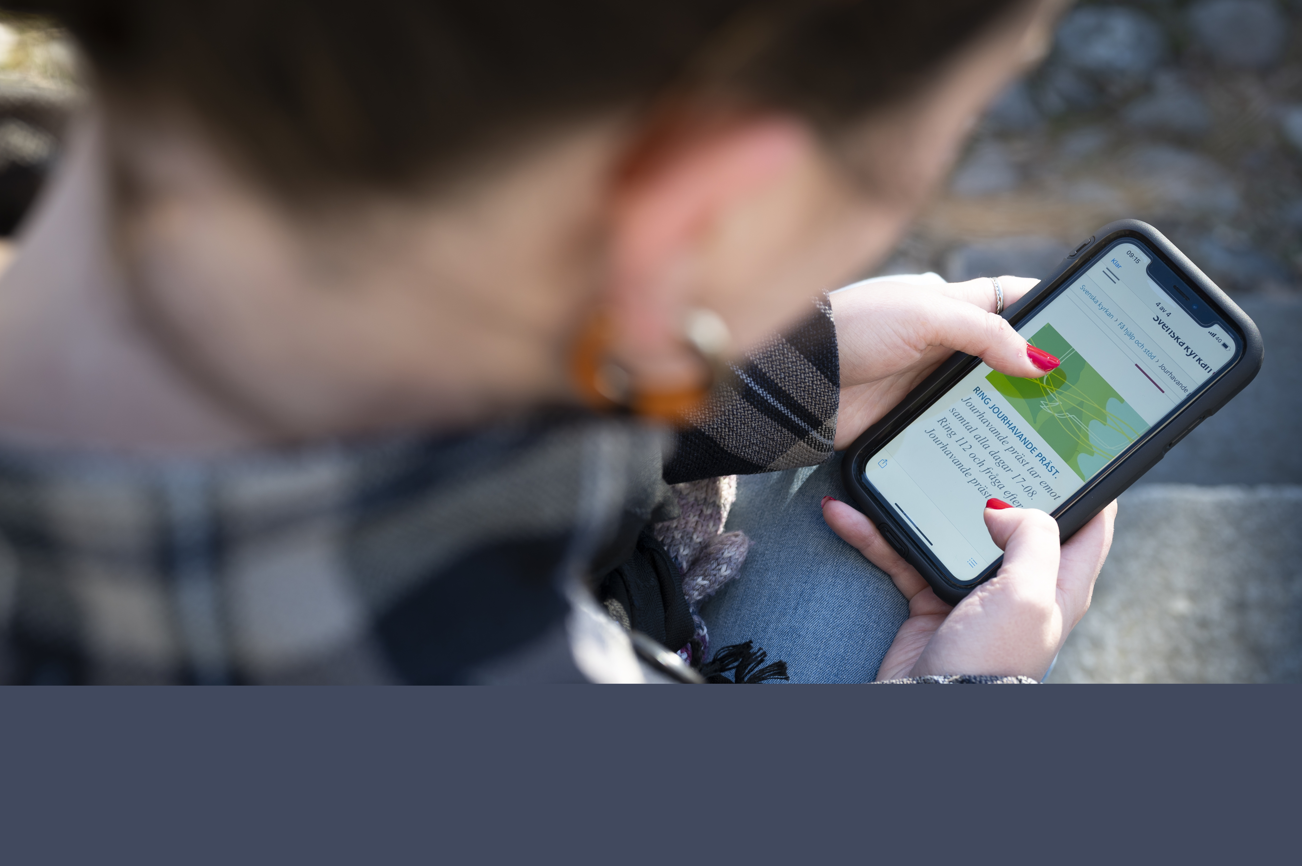 En person med mobilen i knät har surfar in till sidan Jourhavande präst.