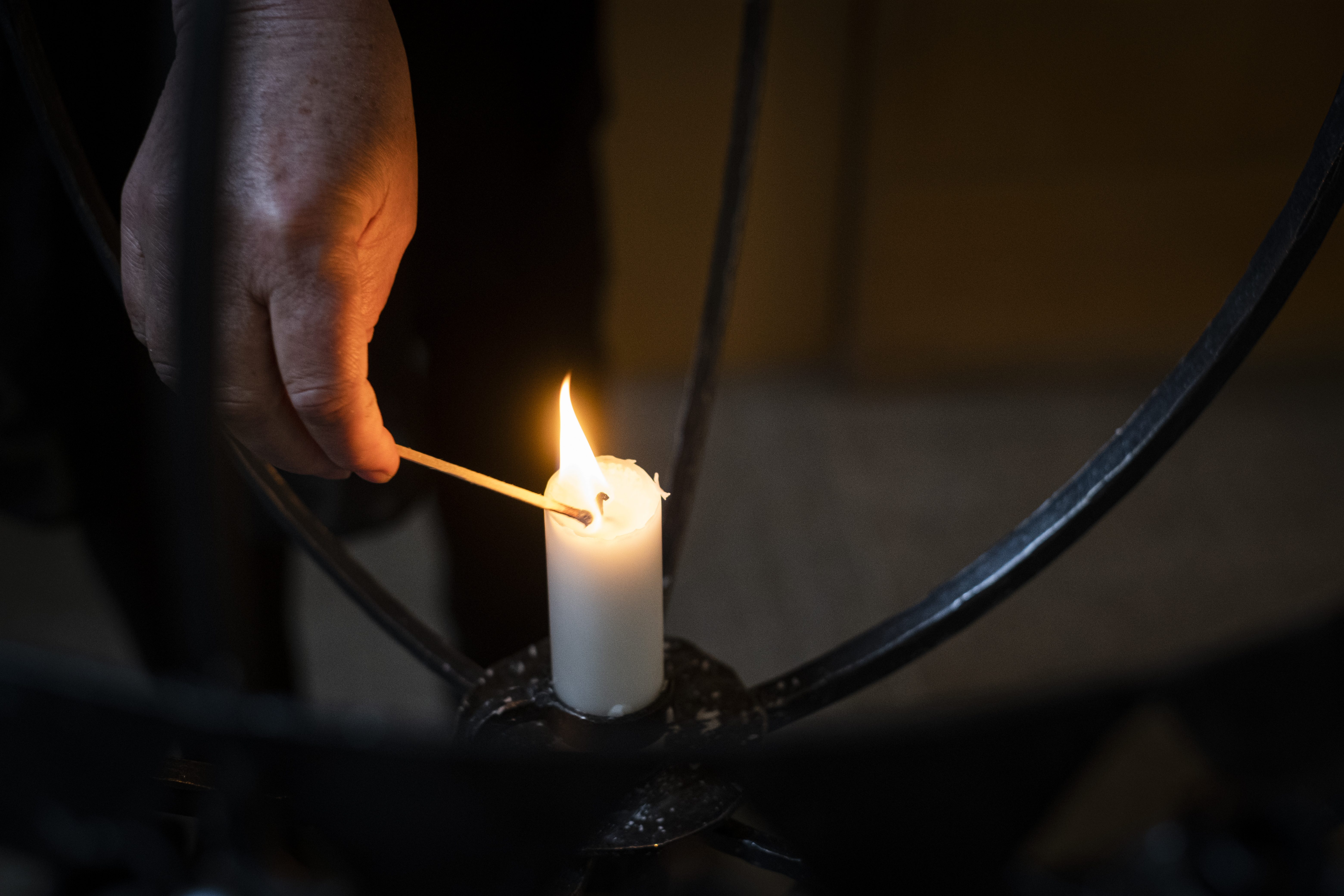 Joku sytyttää kynttelikön kynttilän.