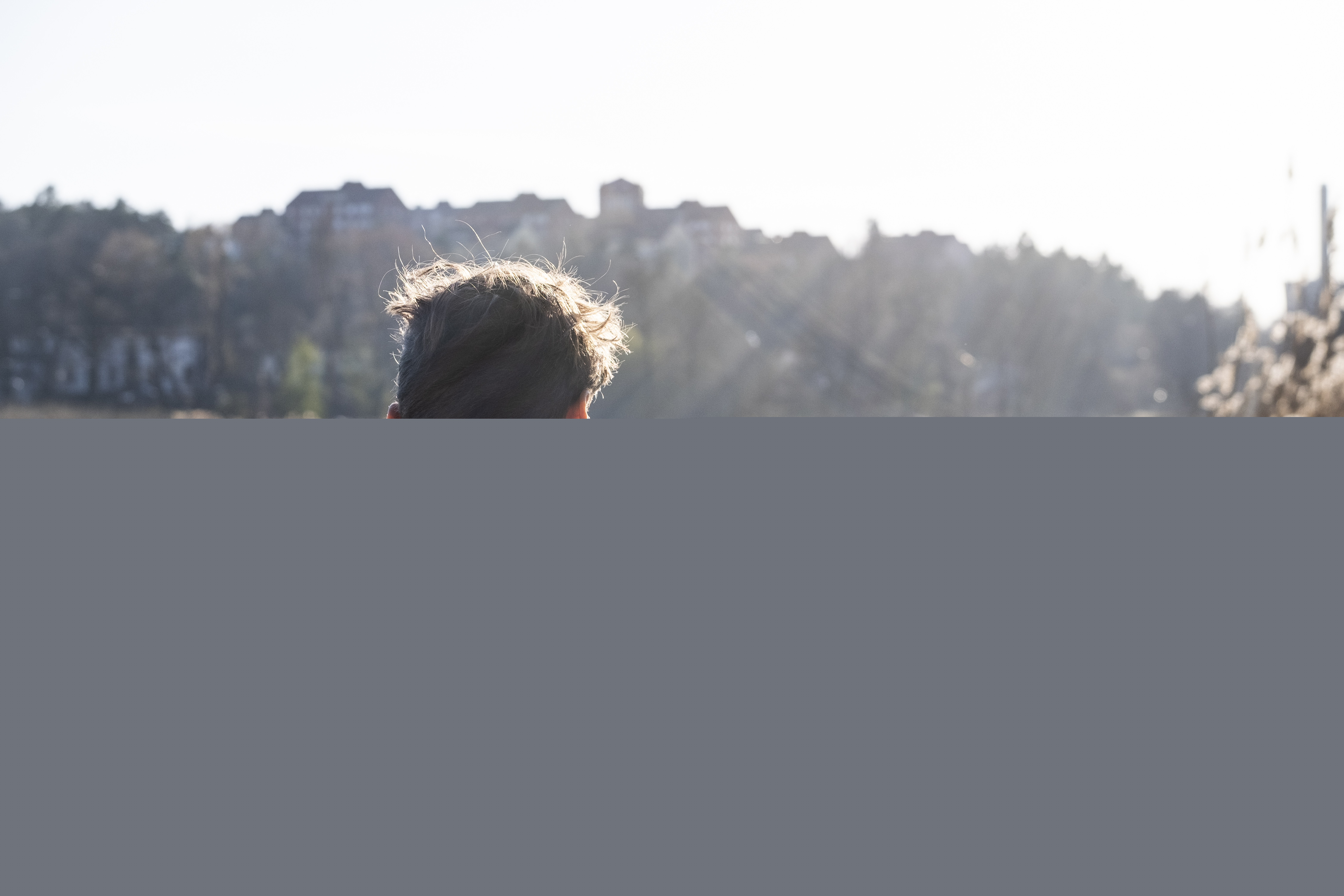 En man med ryggsäck tittar ut över vattnet i solen.