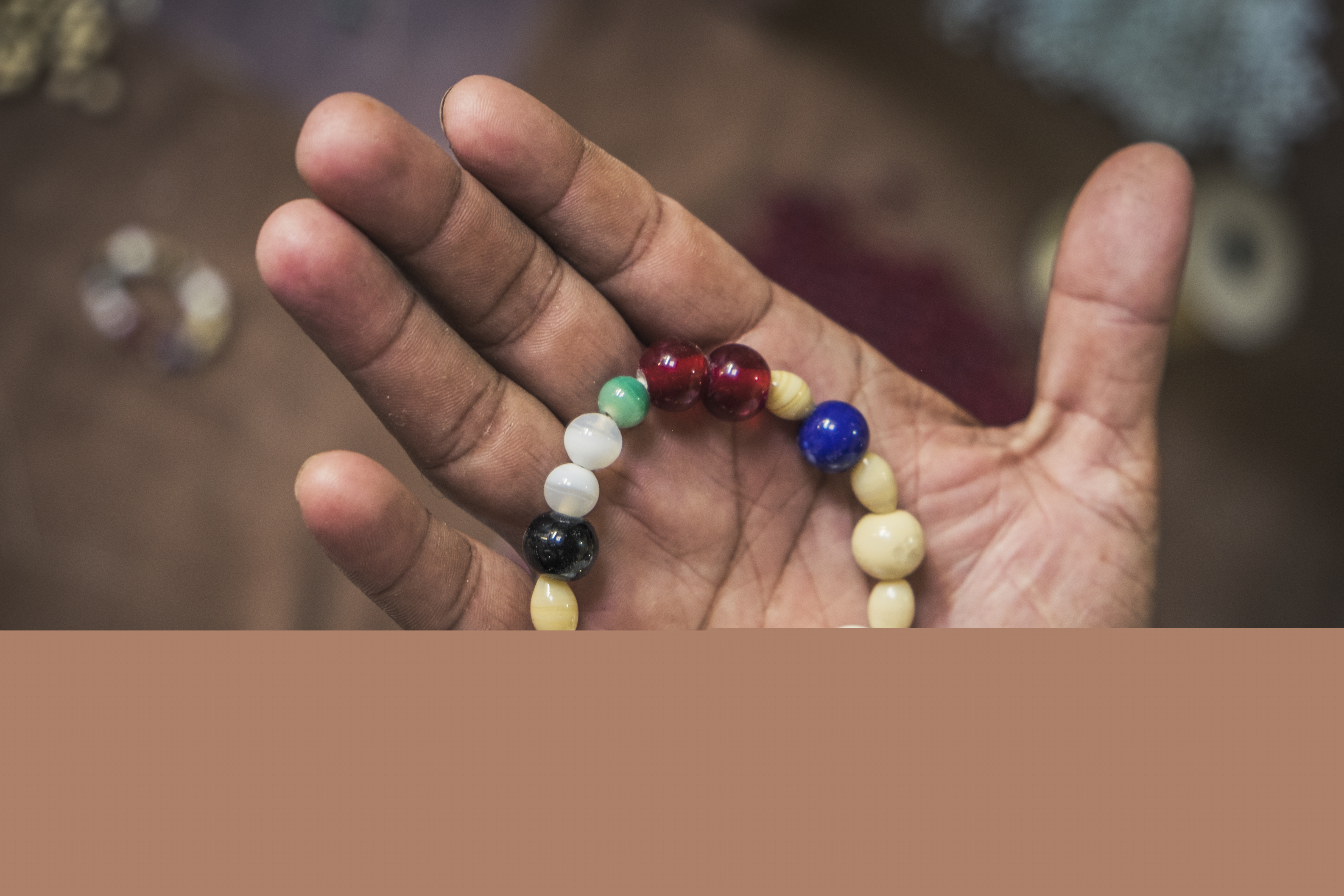 Ett pärlarmband i olika färger ligger i någons hand.