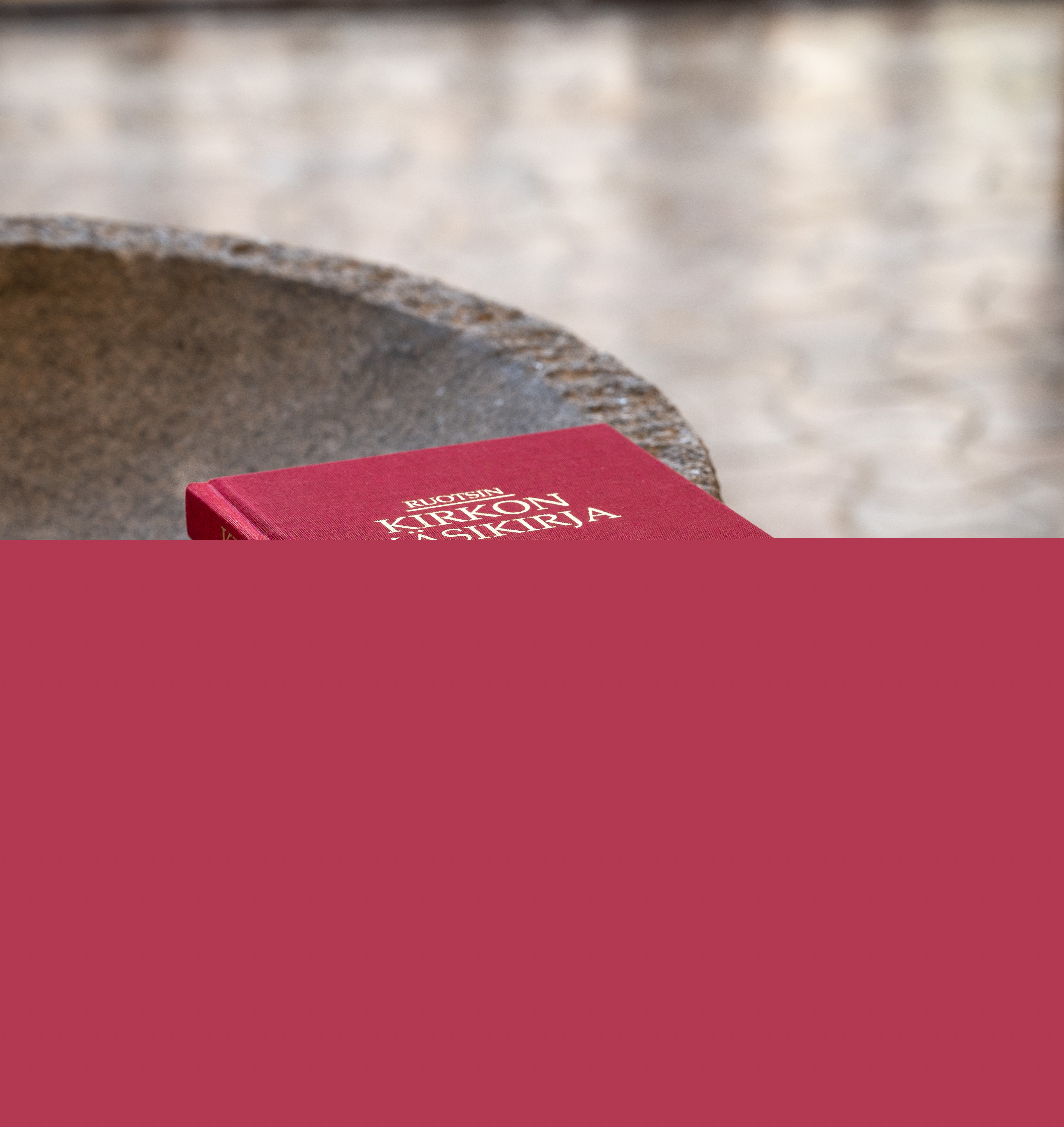 En finsk kyrkohandbok ligger på dopfuntens kant.