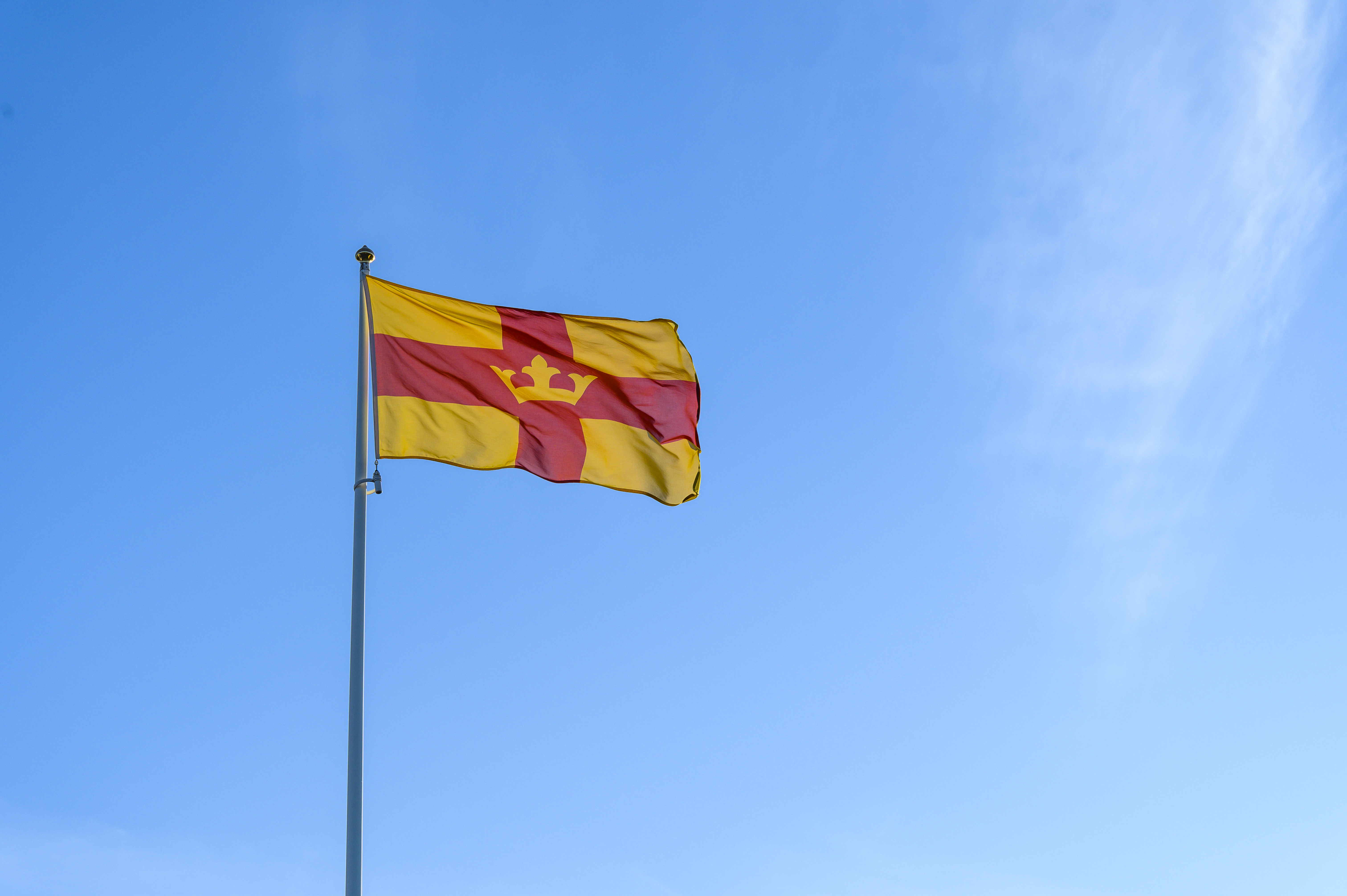 Svenska kyrkans flagga vajar mot en blå himmel.