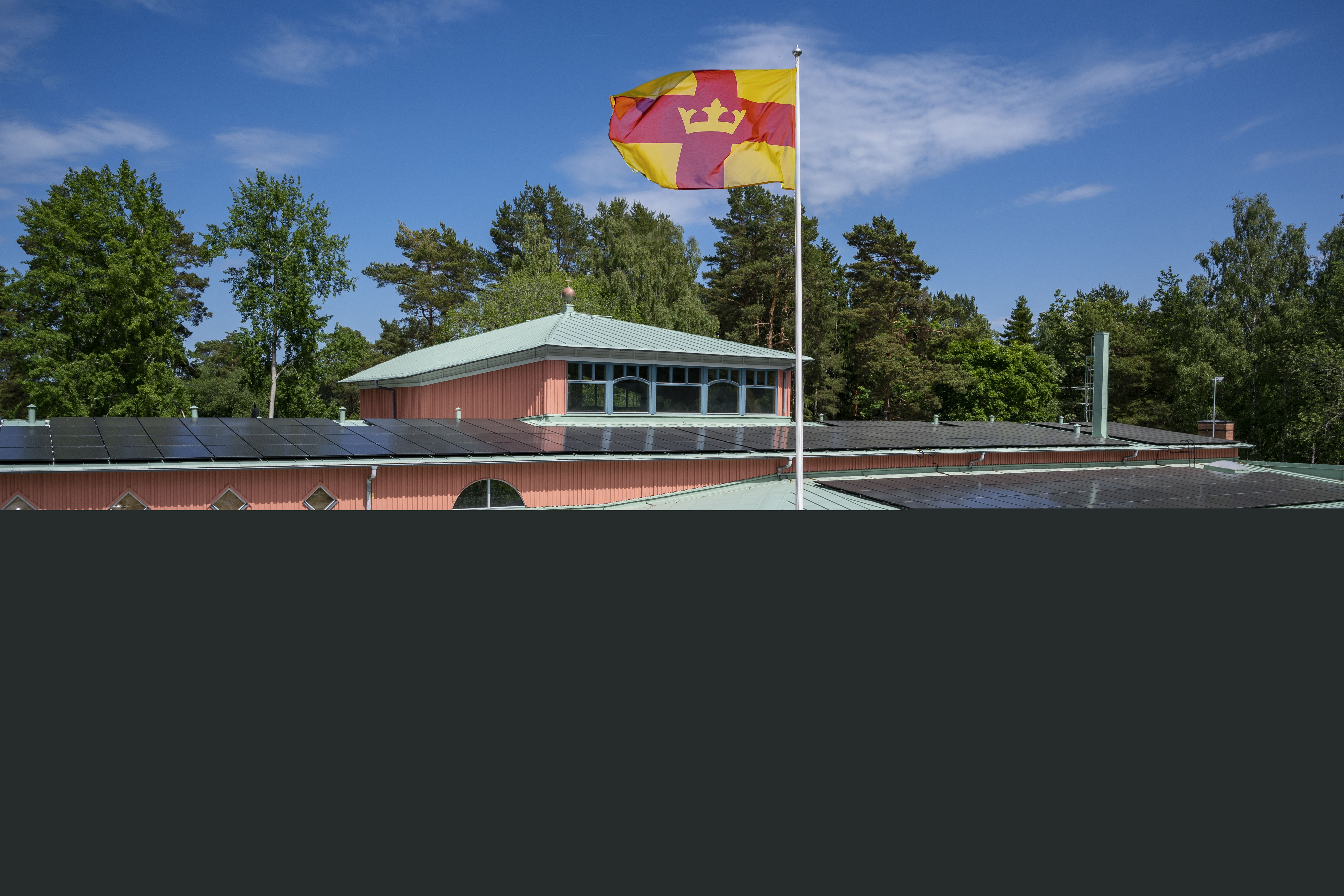 Magdalenakyrkan i Bålsta en solig dag. Svenska kyrkans flagga vajar utanför.
