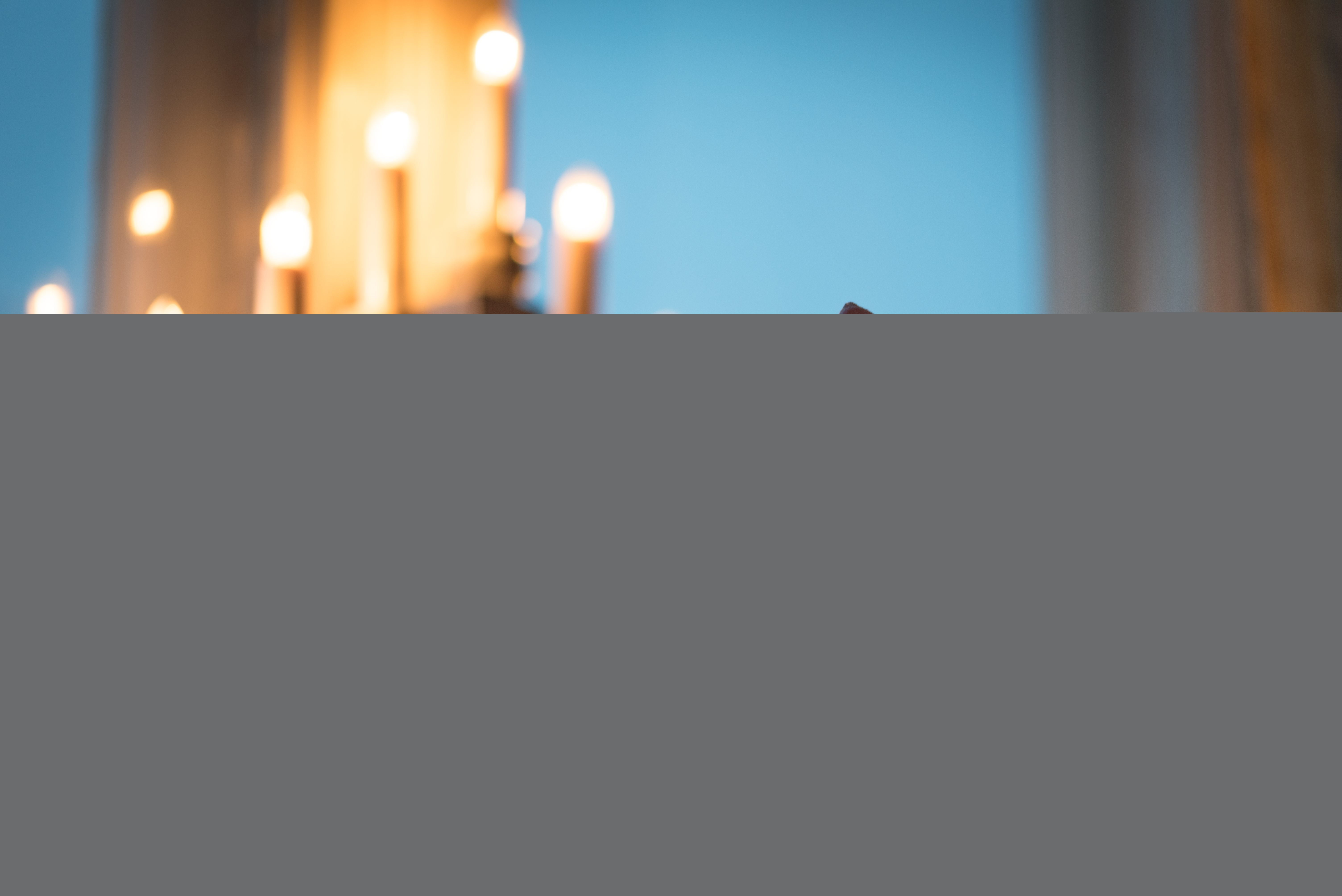 Ett pepparkakshus står framför en adventsljusstake i fönstret.