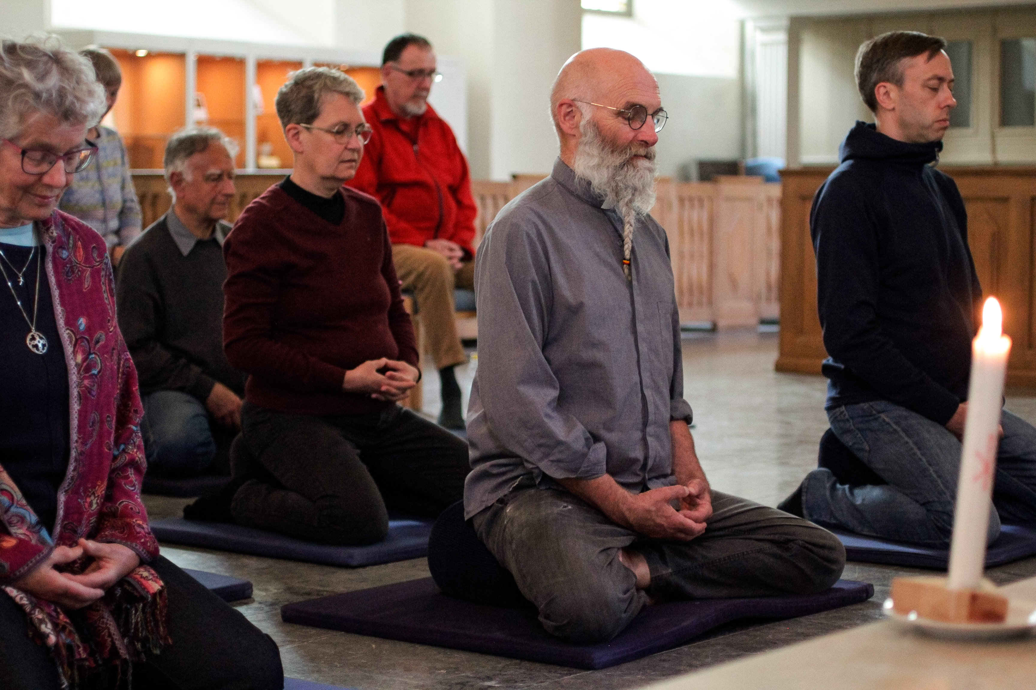 Några personer sitter och mediterar på kyrkans golv.