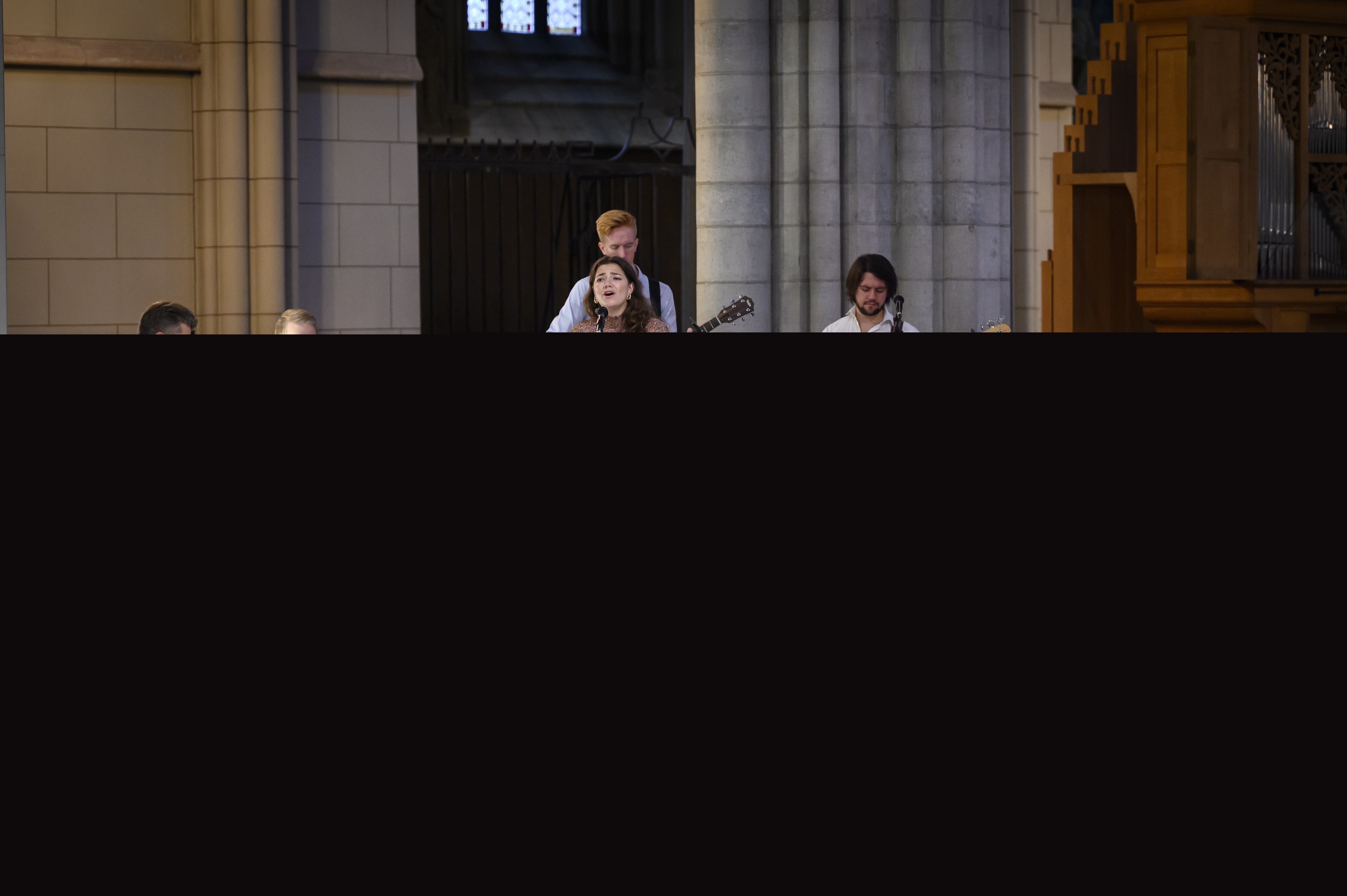 Ett band med trummor, bas, gitarr, piano och en sångerska framför en låt i Uppsala domkyrka.