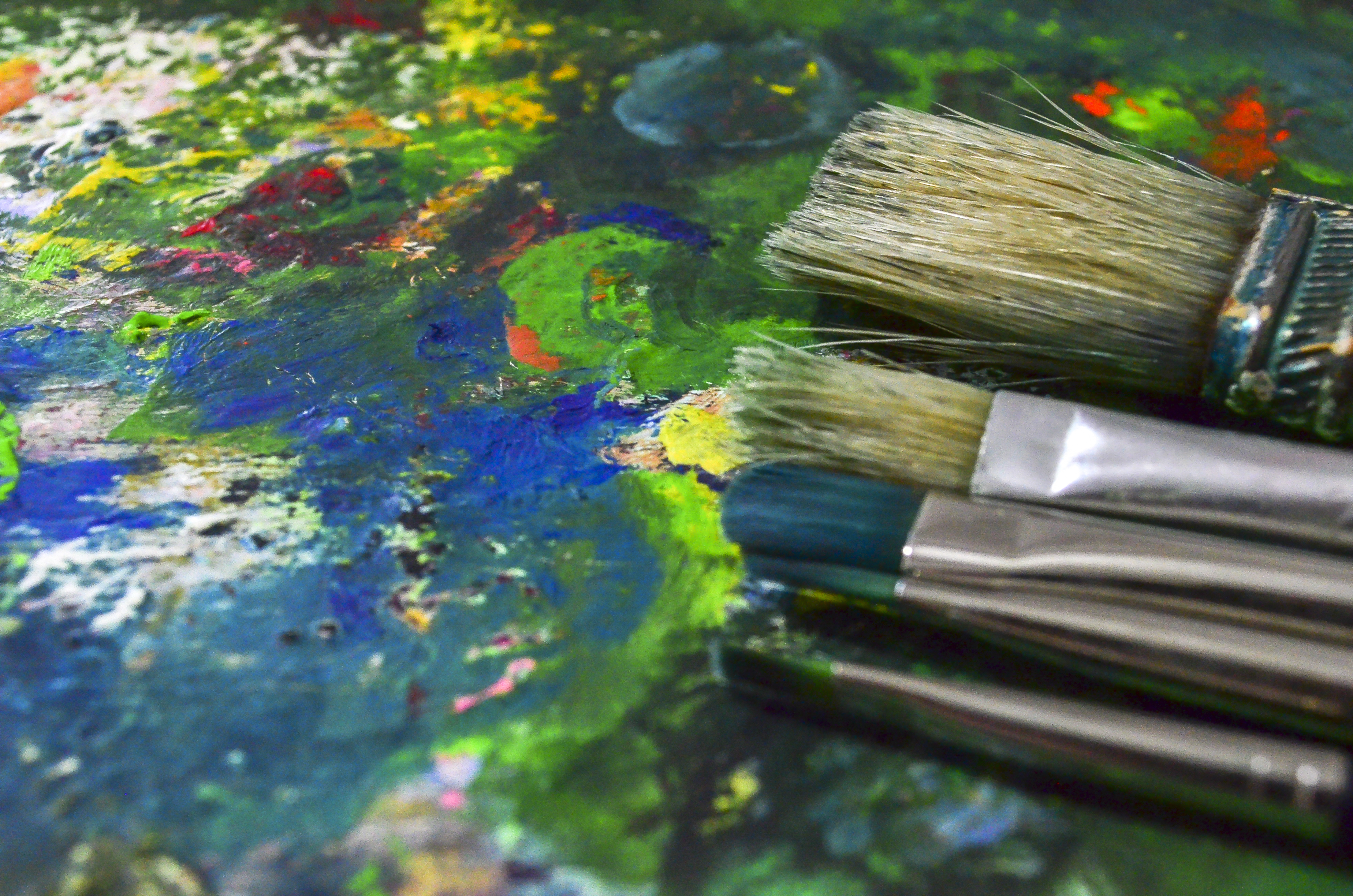 Närbild av målarpenslar på en palett fylld av torkad färg.