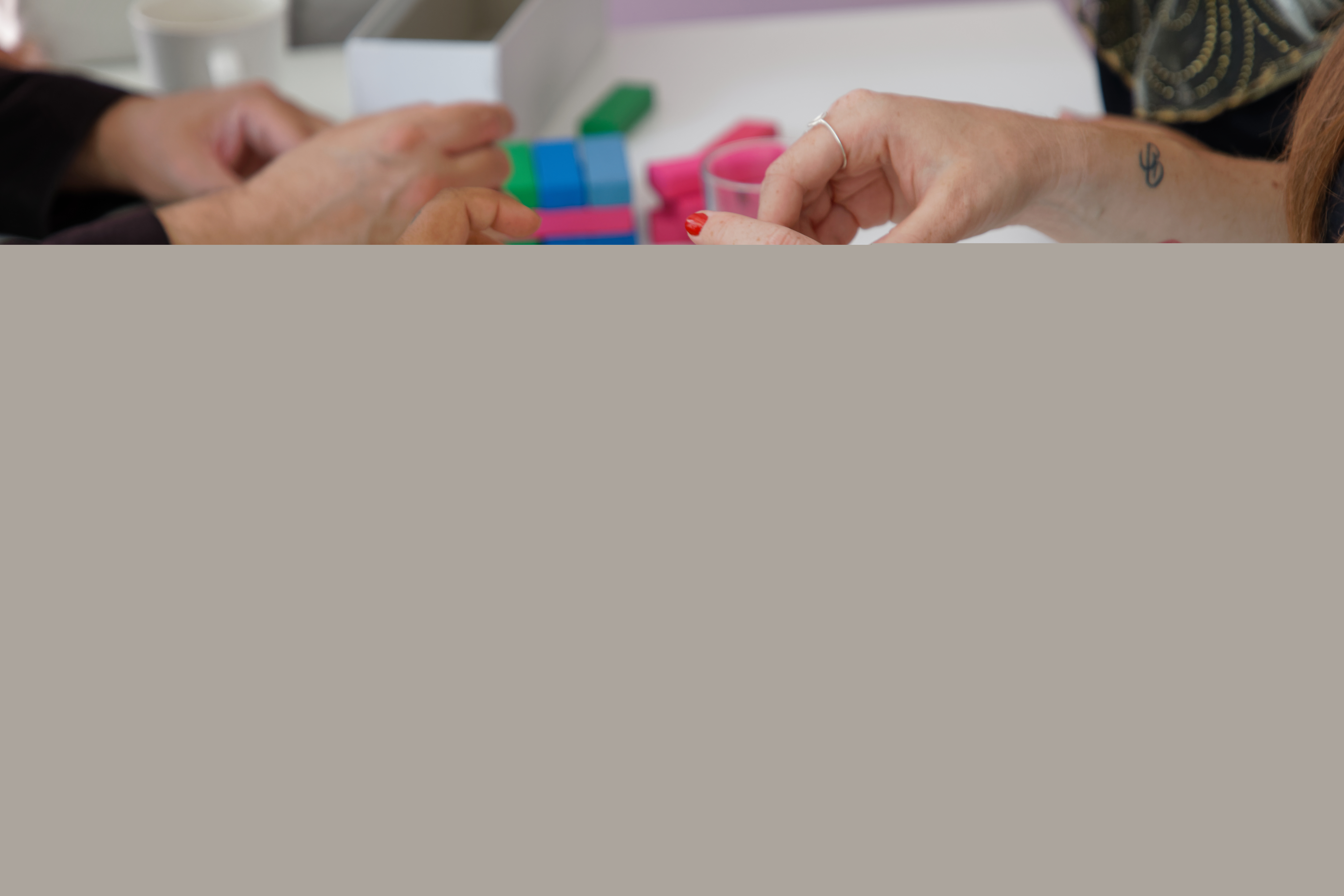 Några personer spelar Jenga med färggranna klossar.