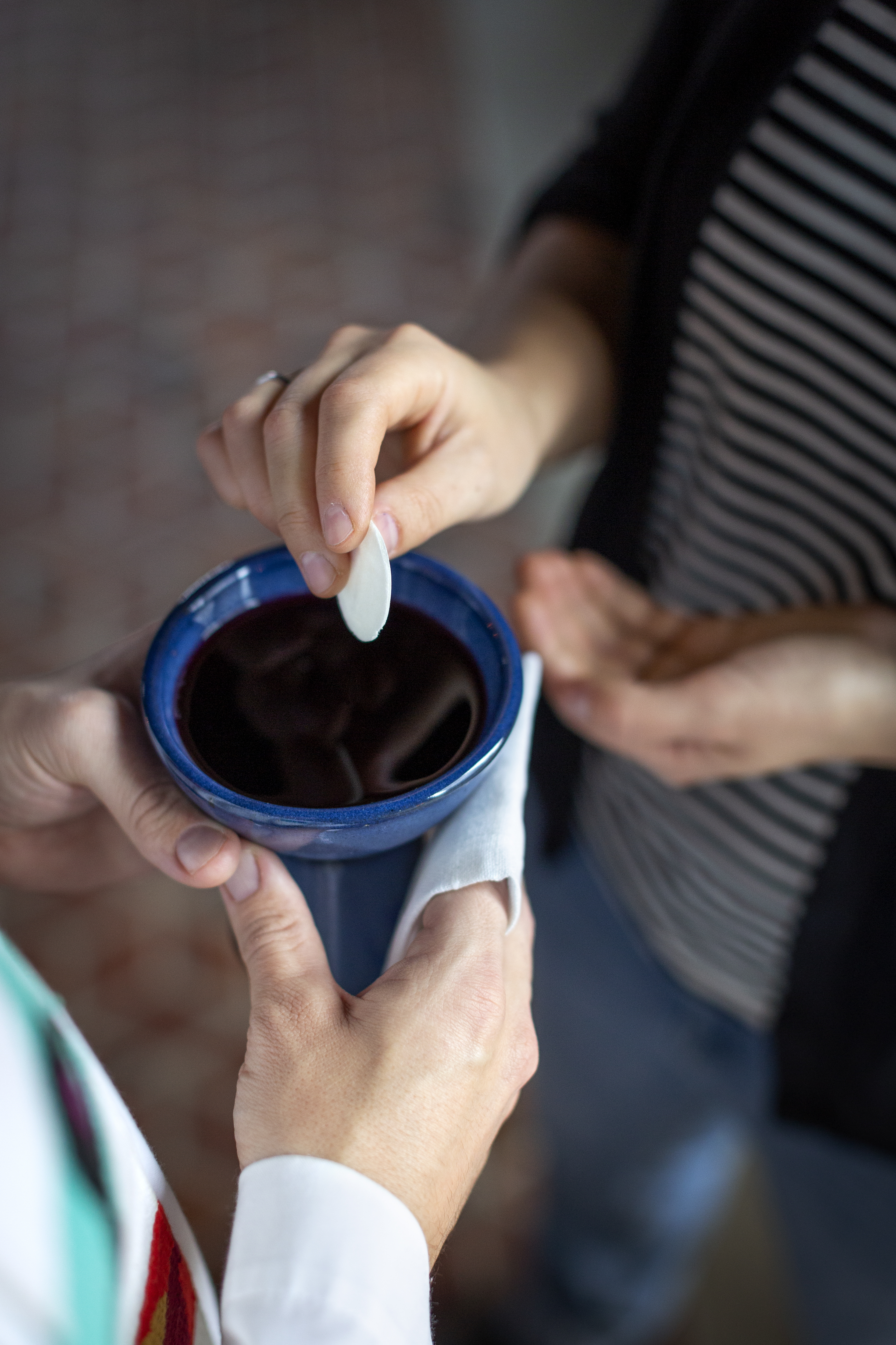 En präst håller fram nattvardskalken och en person doppar sin oblat.